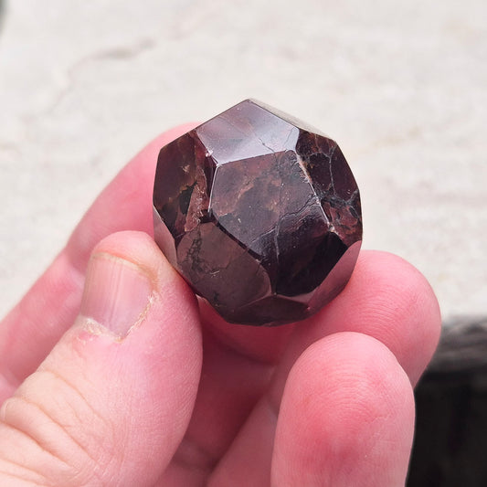 Almandine Garnet Crystal from India, featuring deep reddish-brown hues. Also known as Almandite, this variety of Garnet showcases rich colors ranging from dark reds to purple and brownish reds. 