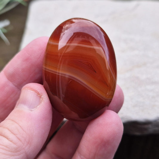 Carnelian Crystal Palm Stone. From Madagascar. This palm stone has a wonderful deep orange colouring and some bading.