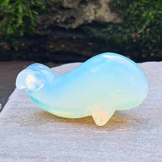 Opalite is a man-made stone that looks like glass. It has a beautiful opalescent appearance with a milky, blueish hue that shifts to a warm glow in certain lighting, resembling the natural iridescence of opal.