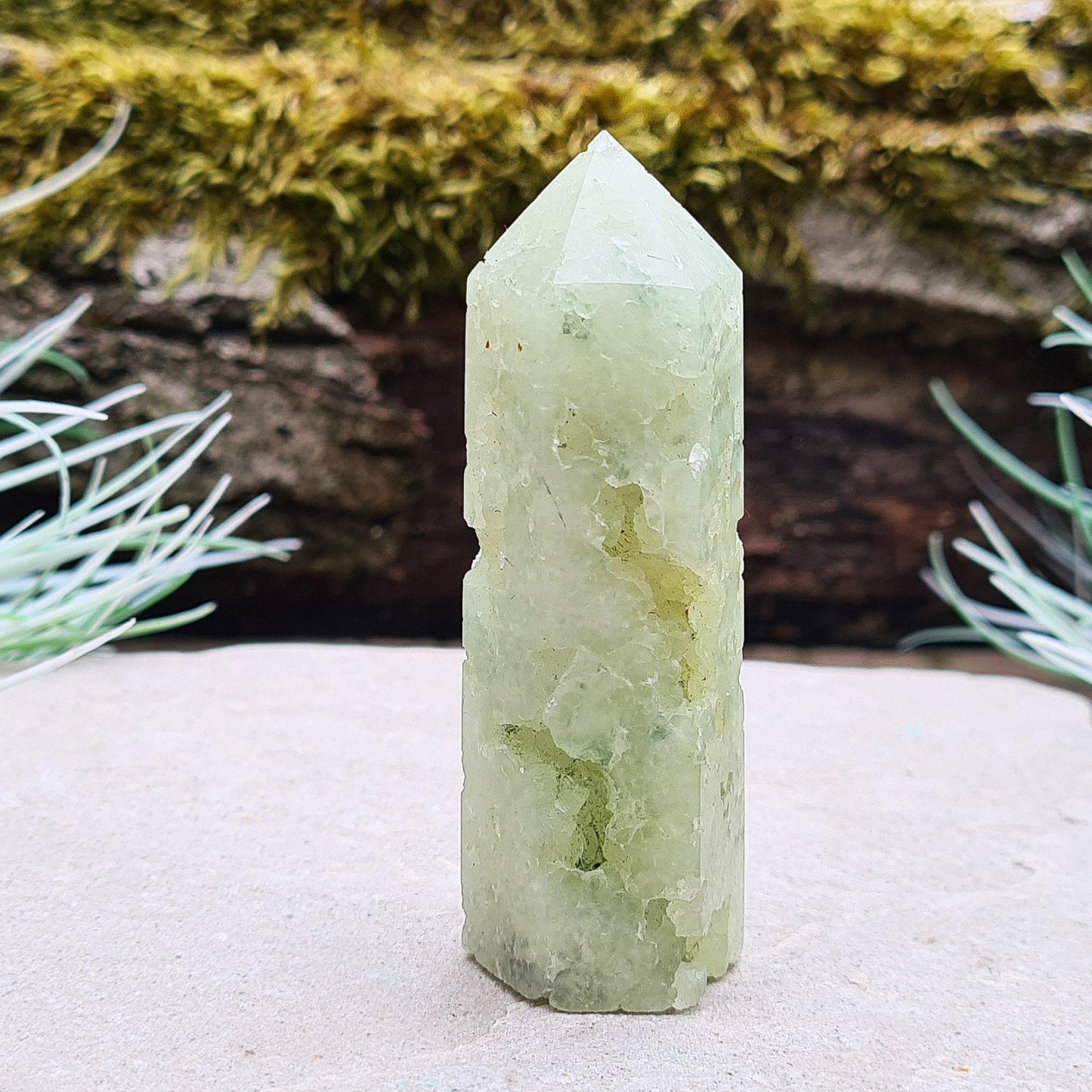 Prehnite Crystal Tower, point is a 6 sided Generator, has lovely natural cavities so you can see the crystalline structure within it. The prehnite is a lovely green. 