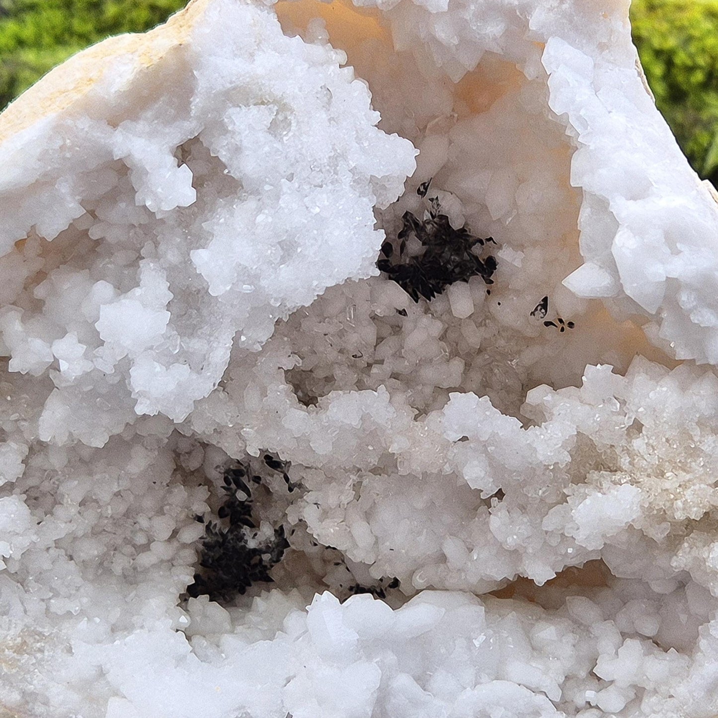 White Quartz Crystal Geode half section, from Morocco. Lovely sparkling white quartz crystal formations and also has 2 areas where there looks to be black quartz, I am assuming a black mineral was present in the geode as the crystalline structure was forming. 