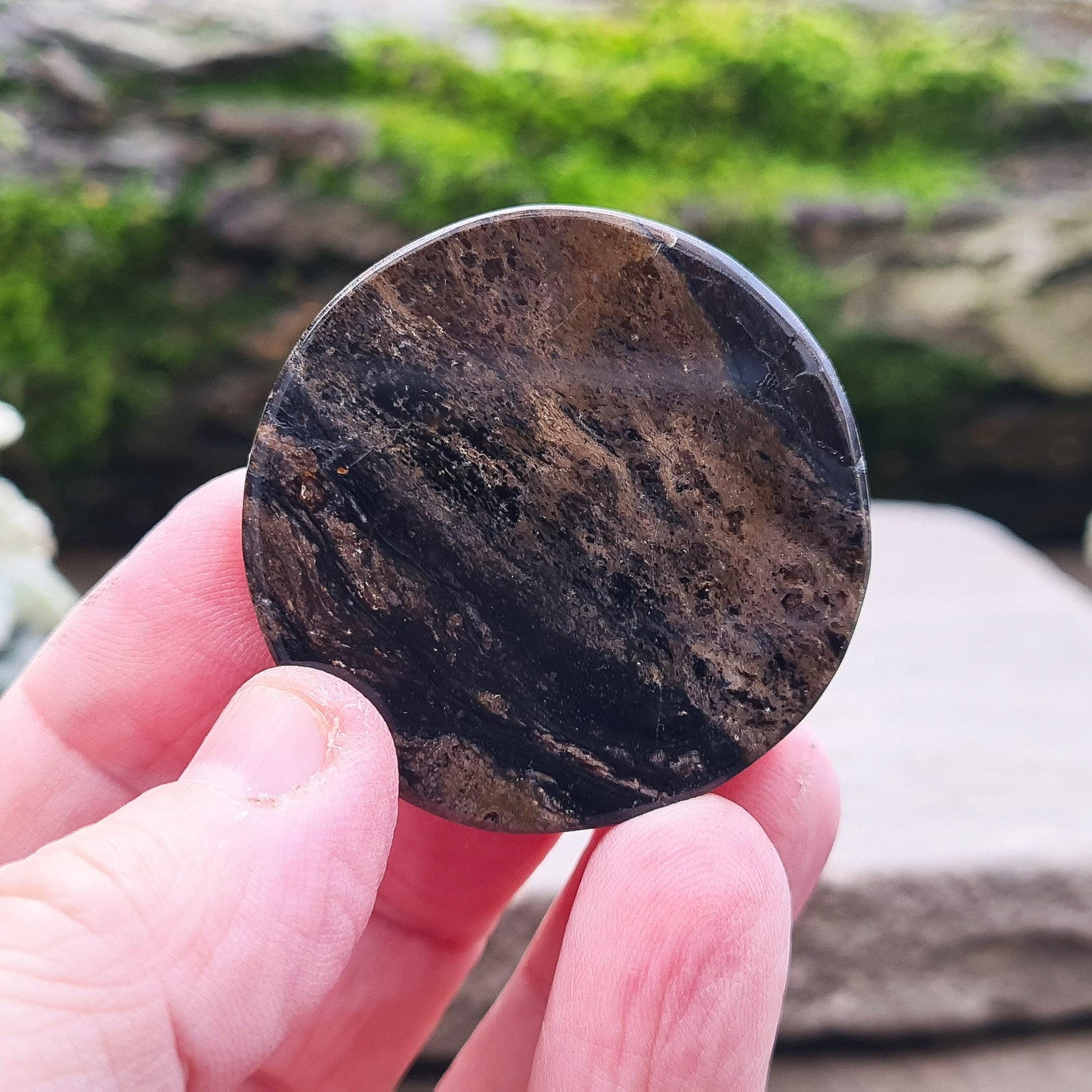 A beautifully polished disk of Obsidian, featuring deep brown and black tones. Smooth and tactile, this piece is perfect for holding during meditation or energy work. Its grounding energy makes it a powerful tool for emotional healing and protection.