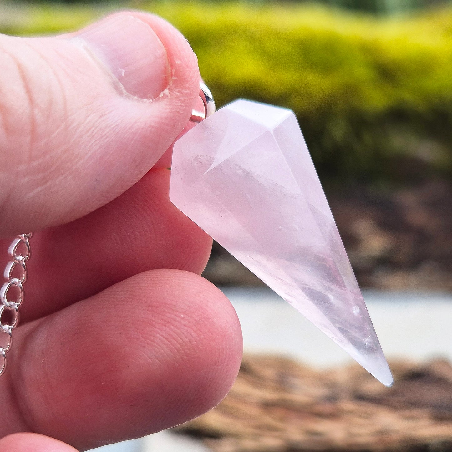 Rose Quartz Crystal Pendulum. comprises of a rose quartz crystal pendulum and a silver ring at the end of the chain. 