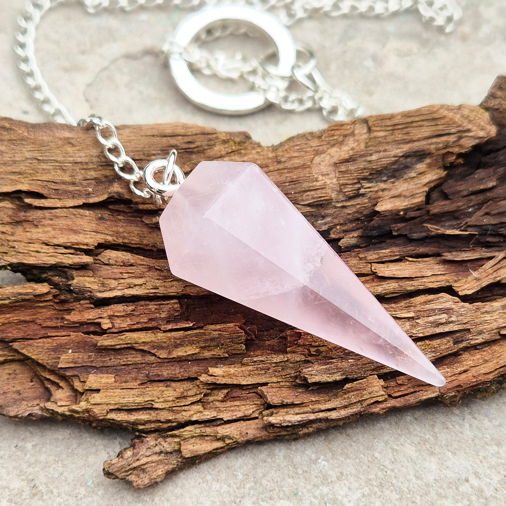 Rose Quartz Crystal Pendulum. comprises of a rose quartz crystal pendulum and a silver ring at the end of the chain. 