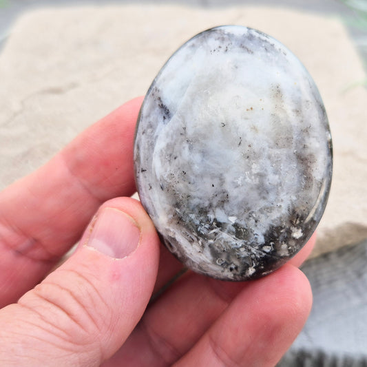 This beautiful Dendritic Opal palm stone features a stunning natural blend of milky white opal with delicate dendritic inclusions. Polished and shaped to fit comfortably in your hand, 