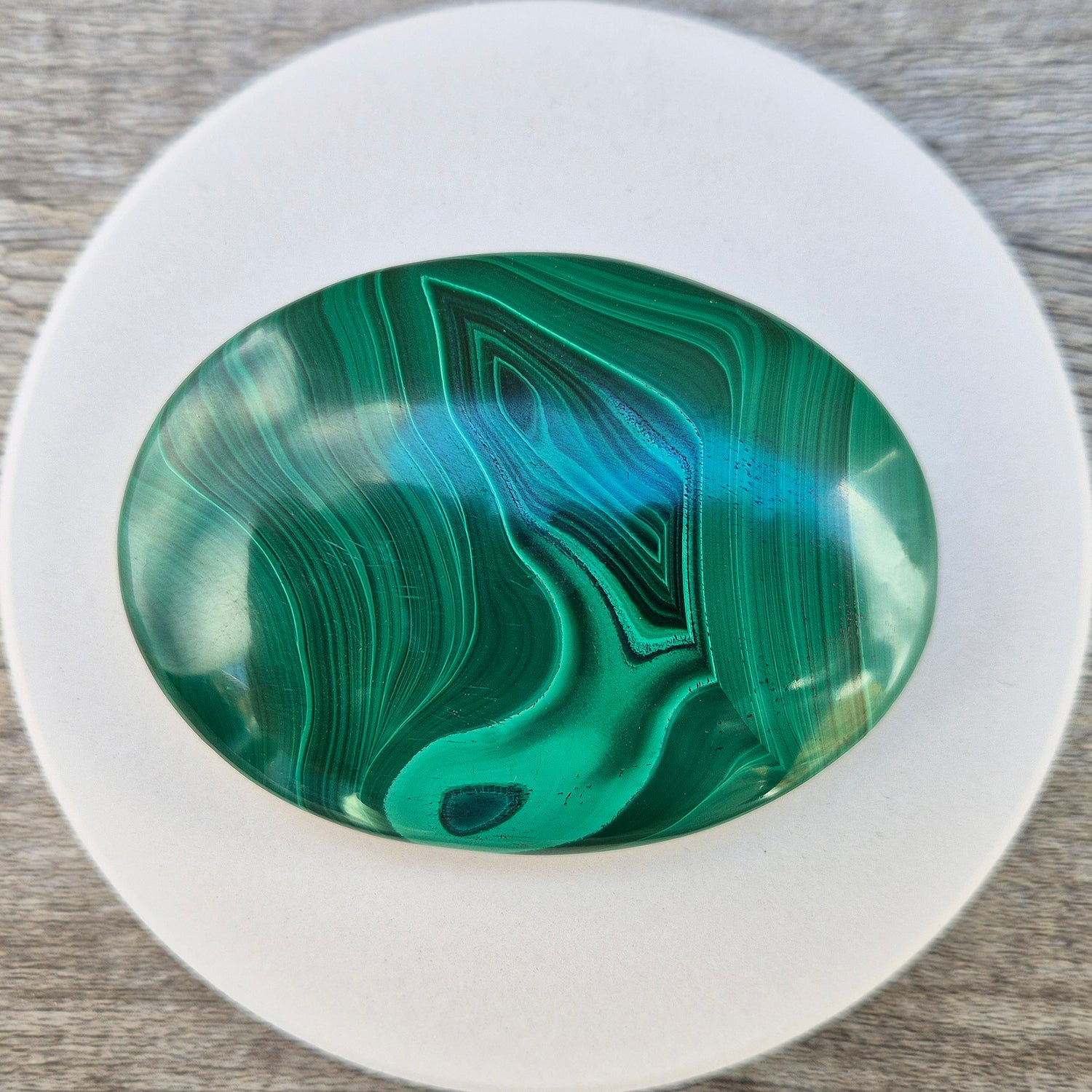 This stunning AA Grade Malachite palm stone features a rich blend of deep green hues and intricate banded patterns, polished for a comfortable feel in your hand. 