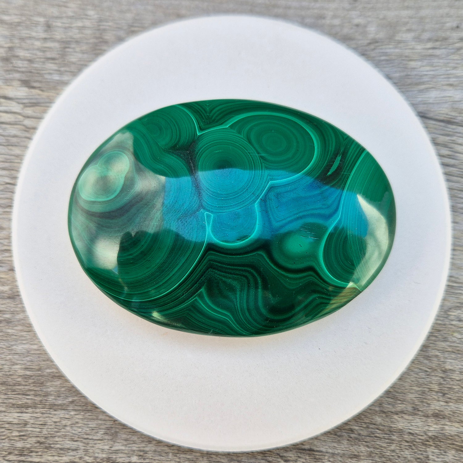 This stunning AA Grade Malachite palm stone features a rich blend of deep green hues and intricate banded patterns, polished for a comfortable feel in your hand. 