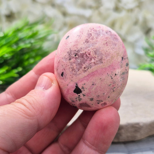 Pink Rhodonite Crystal Palm Stone – Also known as Bubblegum Pink Rhodonite from Peru

This soft pink Rhodonite, with natural black patches from manganese oxidation, is valued for its steady, reassuring energy.