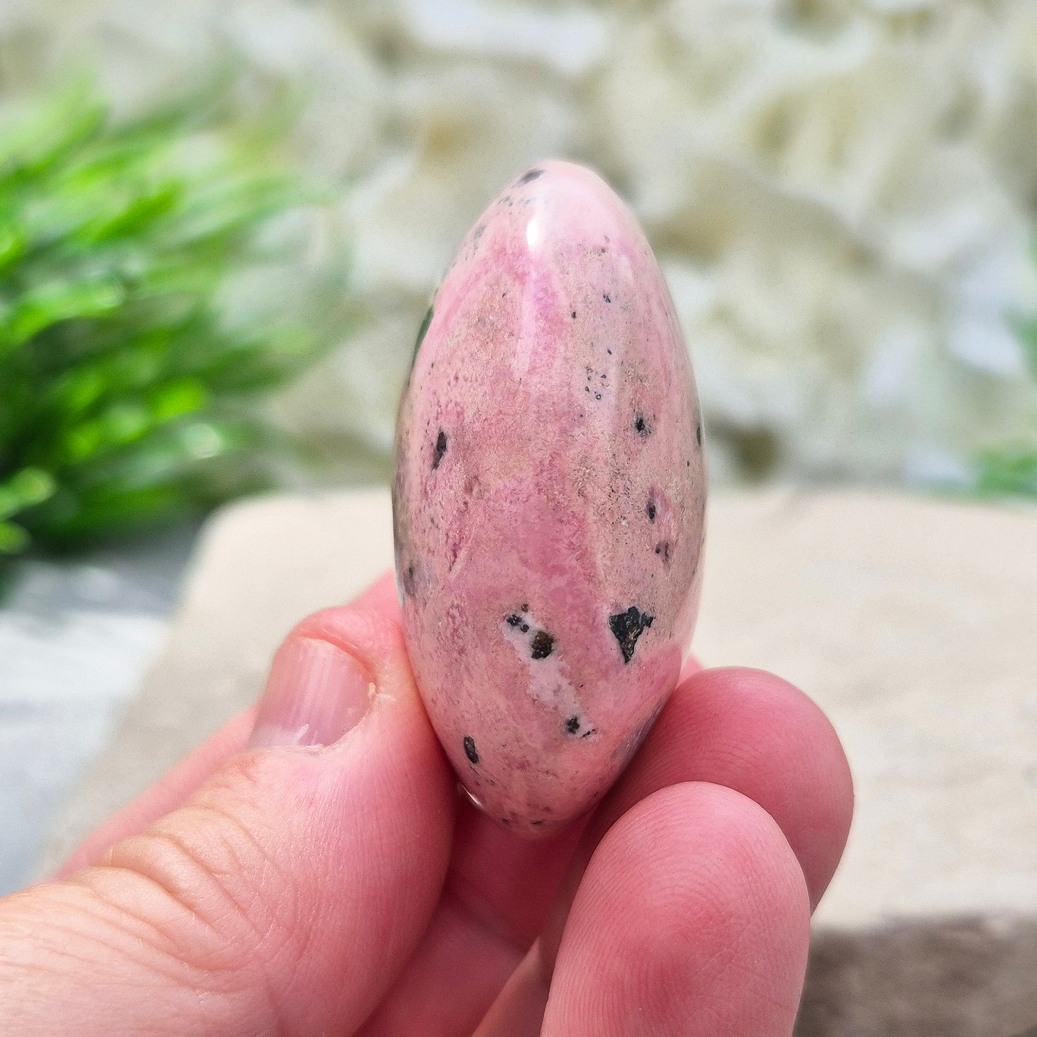 Pink Rhodonite Crystal Palm Stone – Also known as Bubblegum Pink Rhodonite from Peru

This soft pink Rhodonite, with natural black patches from manganese oxidation, is valued for its steady, reassuring energy.