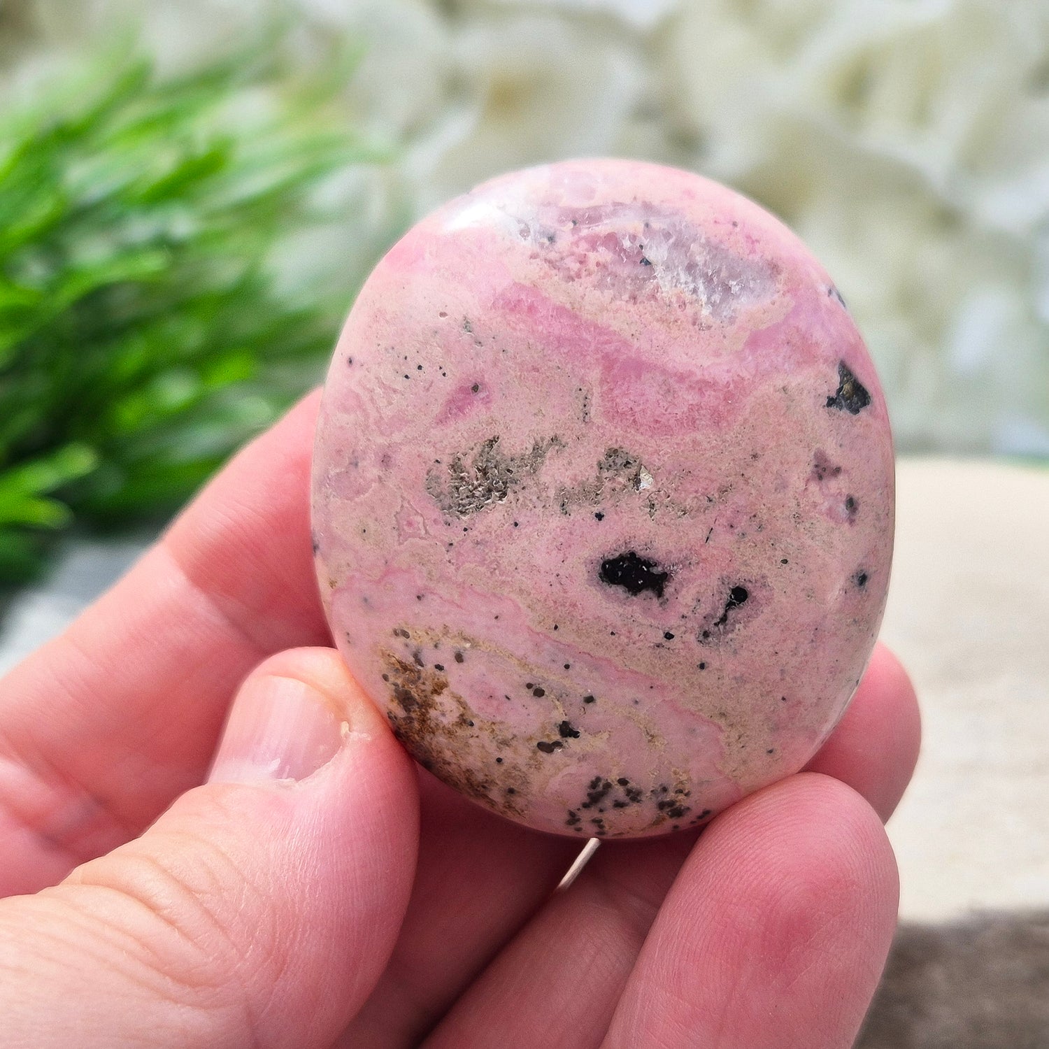 Pink Rhodonite Crystal Palm Stone – Also known as Bubblegum Pink Rhodonite from Peru

This soft pink Rhodonite, with natural black patches from manganese oxidation, is valued for its steady, reassuring energy.