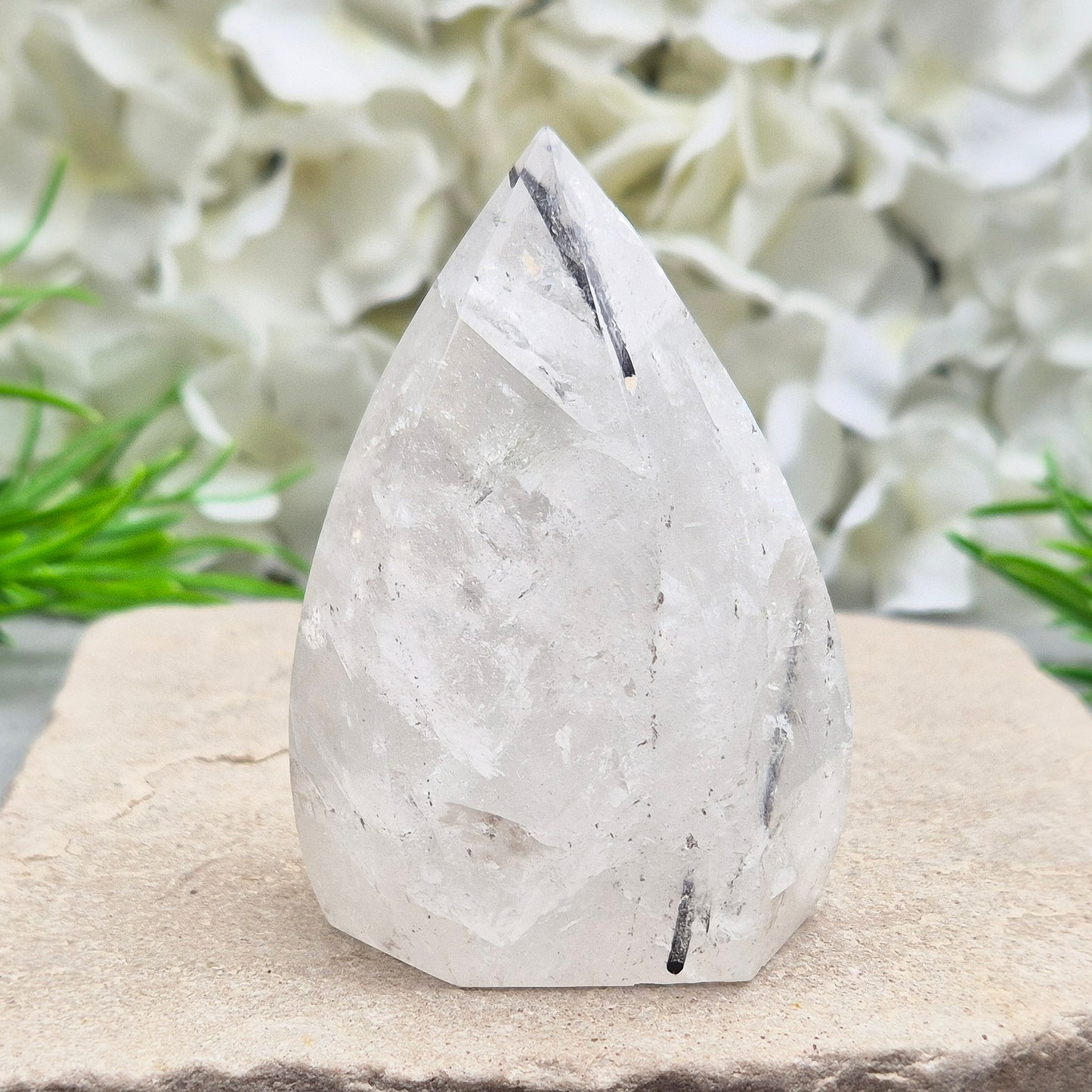 Tourmalinated Quartz Crystal Flame from Brazil radiates both clarity and grounded strength. This striking piece combines the amplifying energy of clear Quartz with the protective, stabilising force of Black Tourmaline. Formed into a polished flame shape