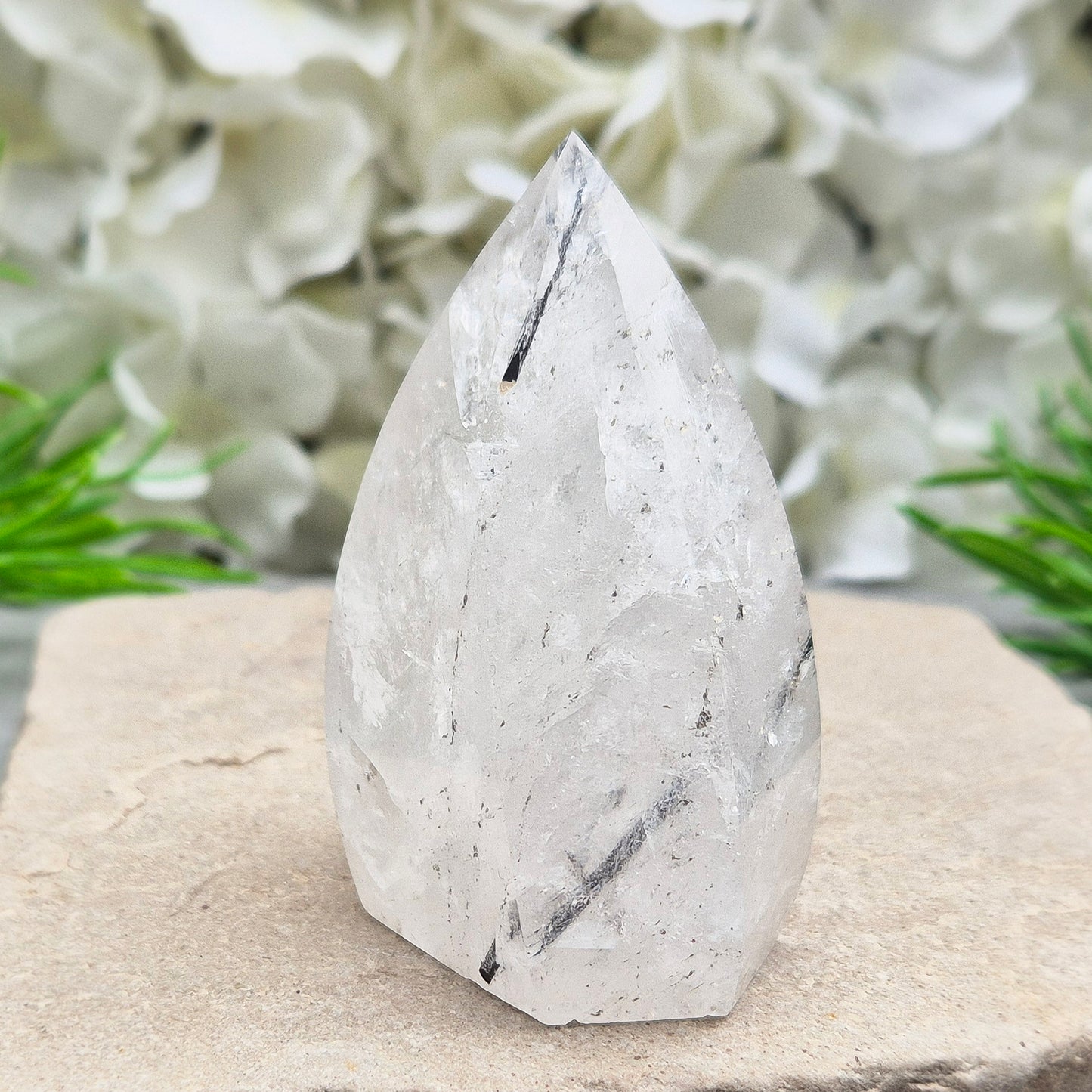 Tourmalinated Quartz Crystal Flame from Brazil radiates both clarity and grounded strength. This striking piece combines the amplifying energy of clear Quartz with the protective, stabilising force of Black Tourmaline. Formed into a polished flame shape