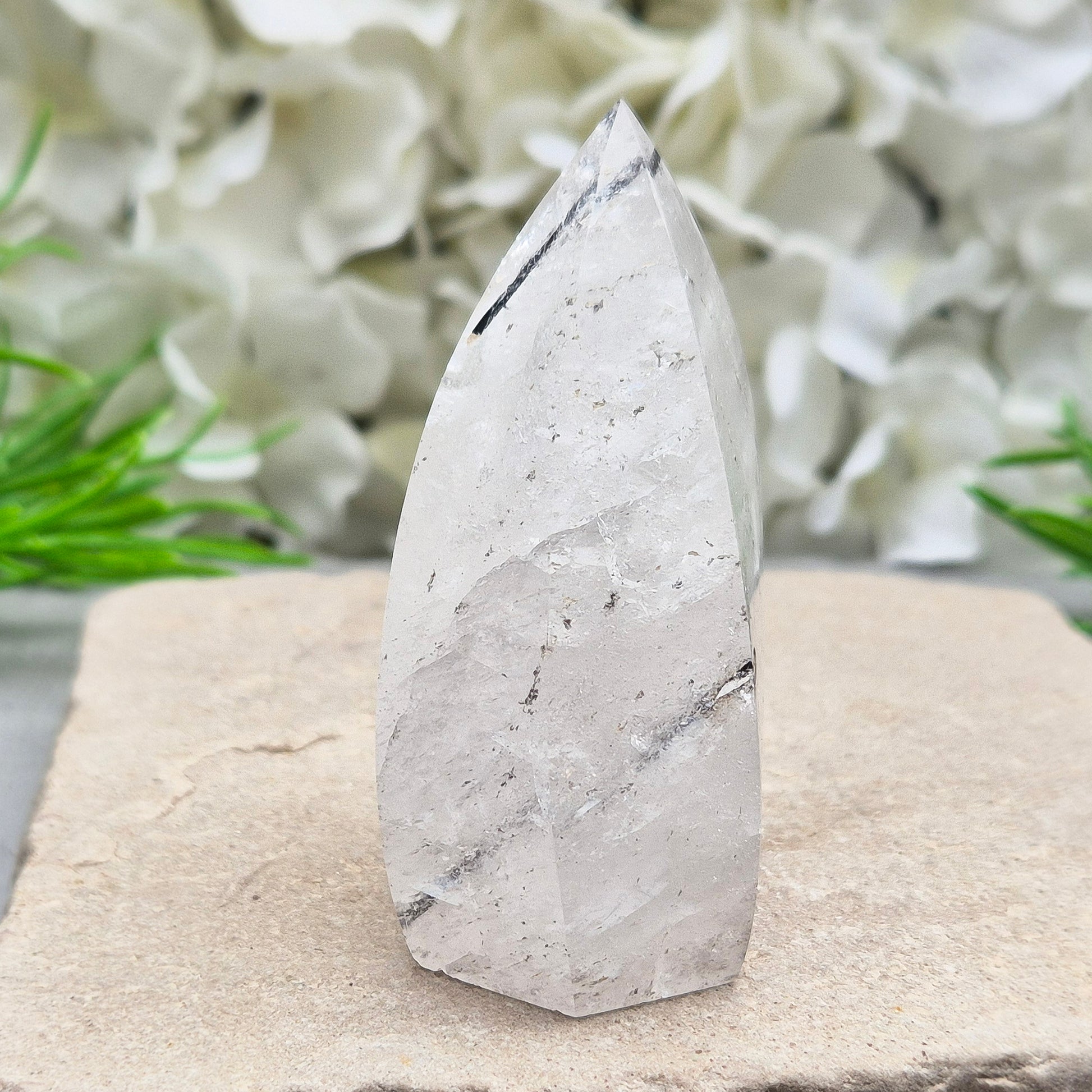 Tourmalinated Quartz Crystal Flame from Brazil radiates both clarity and grounded strength. This striking piece combines the amplifying energy of clear Quartz with the protective, stabilising force of Black Tourmaline. Formed into a polished flame shape