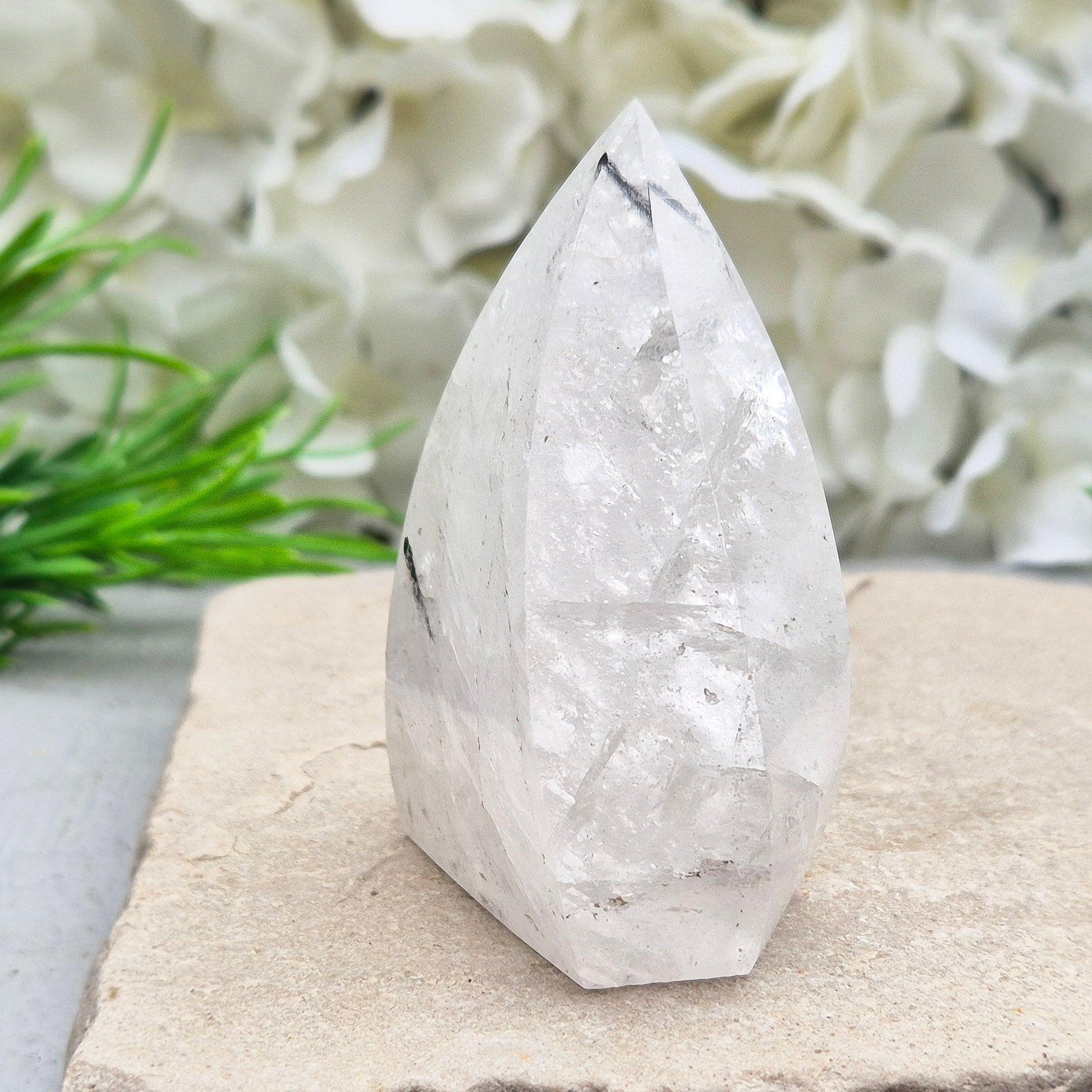 Tourmalinated Quartz Crystal Flame from Brazil radiates both clarity and grounded strength. This striking piece combines the amplifying energy of clear Quartz with the protective, stabilising force of Black Tourmaline. Formed into a polished flame shape