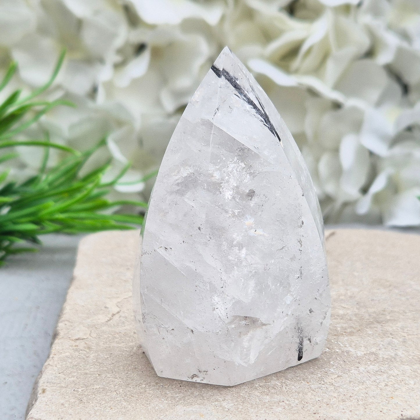 Tourmalinated Quartz Crystal Flame from Brazil radiates both clarity and grounded strength. This striking piece combines the amplifying energy of clear Quartz with the protective, stabilising force of Black Tourmaline. Formed into a polished flame shape