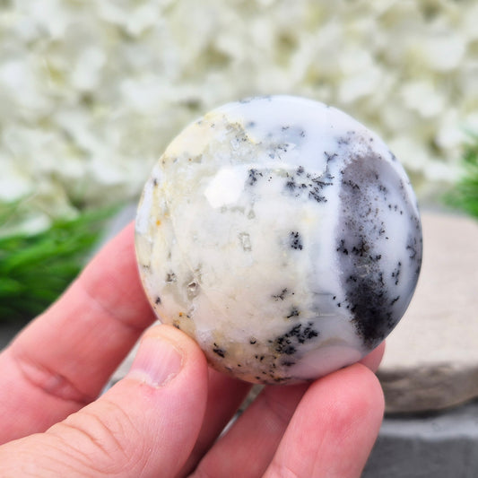 This stunning Merlinite galet from Madagascar features soft off-white and grey colouring with black dendritic (fern-like) inclusions of Psilomelane. Its polished, circular shape makes it a perfect tactile piece for meditation and spiritual work.