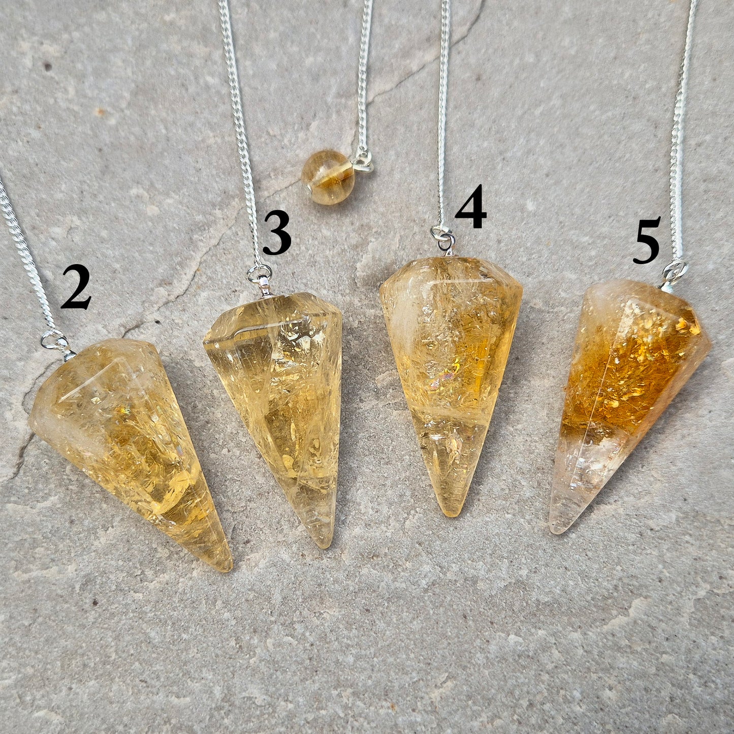 Citrine Crystal Pendulum from Brazil. These stunning sunny pendulums carry the warm, golden glow Citrine is loved for. Each has a yellow bead at the end of the chain making it comfortable to hold and easy to use. 