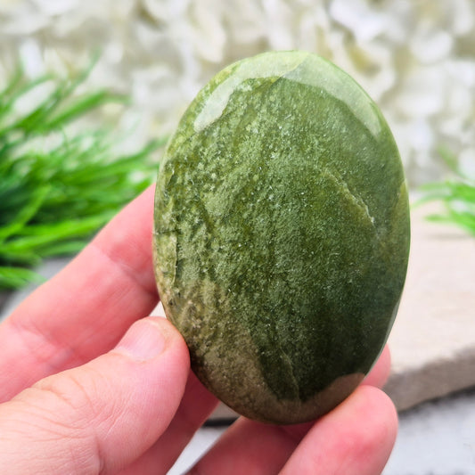 This lovely Tremolite palm stone from the United States shows soft green colouring with a smooth, polished finish. Tremolite forms when rocks such as limestone undergo heat and pressure, creating a crystal that appears in shades of white, grey, green, or light brown.