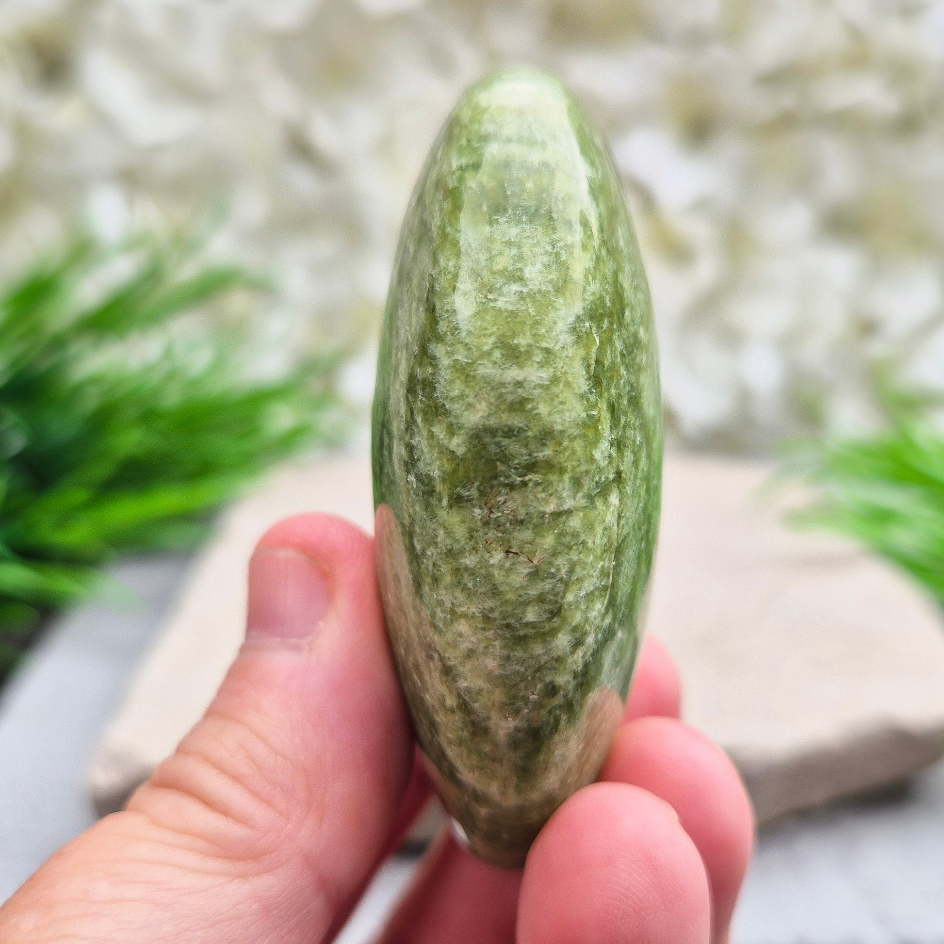 This lovely Tremolite palm stone from the United States shows soft green colouring with a smooth, polished finish. Tremolite forms when rocks such as limestone undergo heat and pressure, creating a crystal that appears in shades of white, grey, green, or light brown.