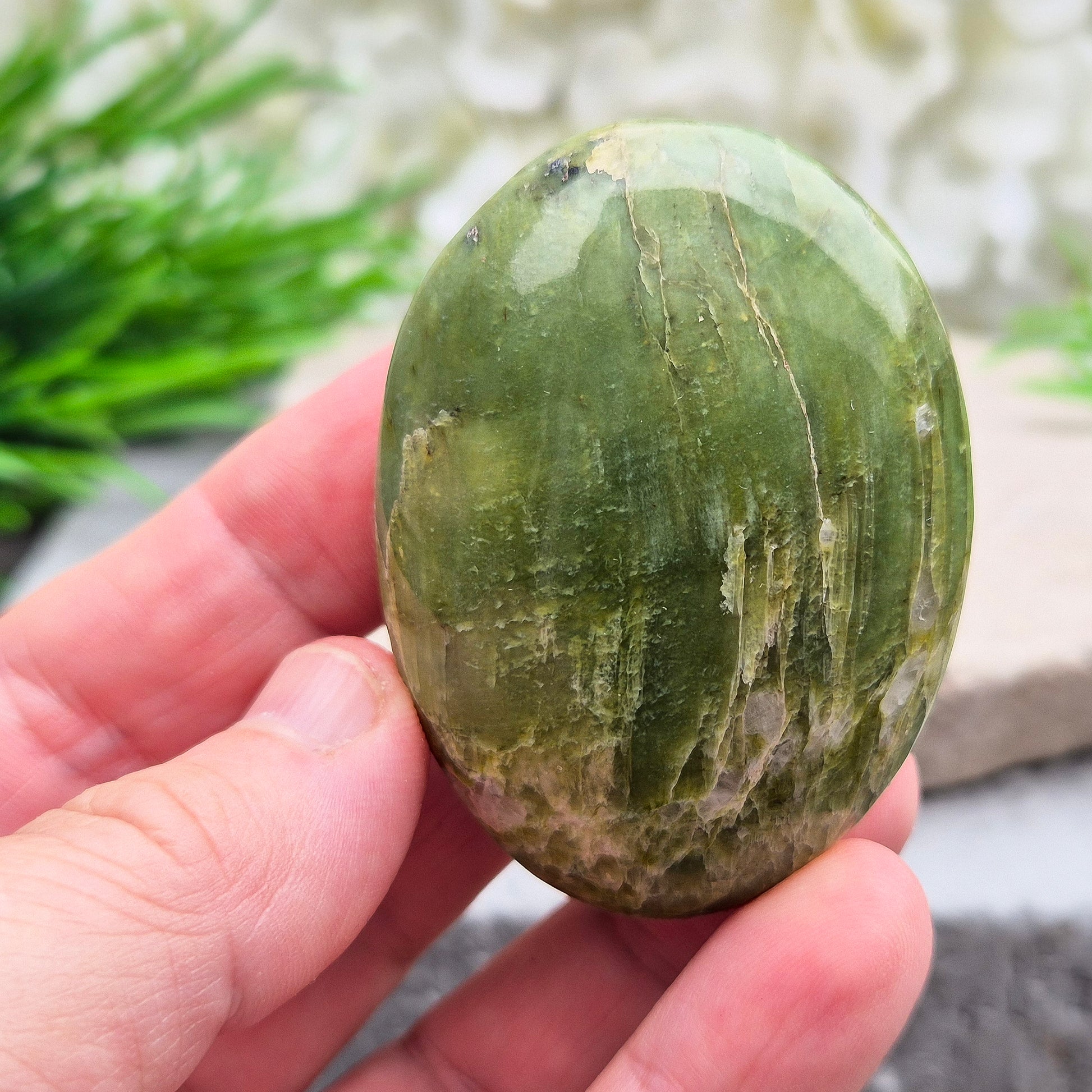 This lovely Tremolite palm stone from the United States shows soft green colouring with a smooth, polished finish. Tremolite forms when rocks such as limestone undergo heat and pressure, creating a crystal that appears in shades of white, grey, green, or light brown.