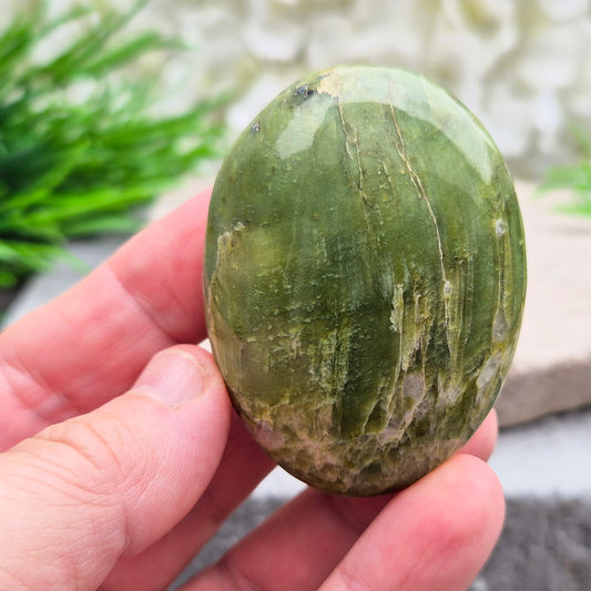 This lovely Tremolite palm stone from the United States shows soft green colouring with a smooth, polished finish. Tremolite forms when rocks such as limestone undergo heat and pressure, creating a crystal that appears in shades of white, grey, green, or light brown.