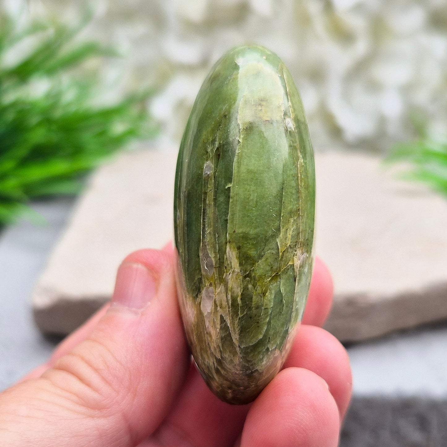 This lovely Tremolite palm stone from the United States shows soft green colouring with a smooth, polished finish. Tremolite forms when rocks such as limestone undergo heat and pressure, creating a crystal that appears in shades of white, grey, green, or light brown.