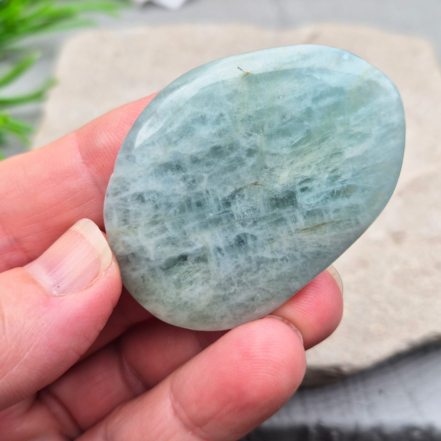 Aquamarine palm stone in pale aqua-blue, polished smooth. A calming crystal linked to the throat chakra, ideal for clearer thinking and honest conversations.