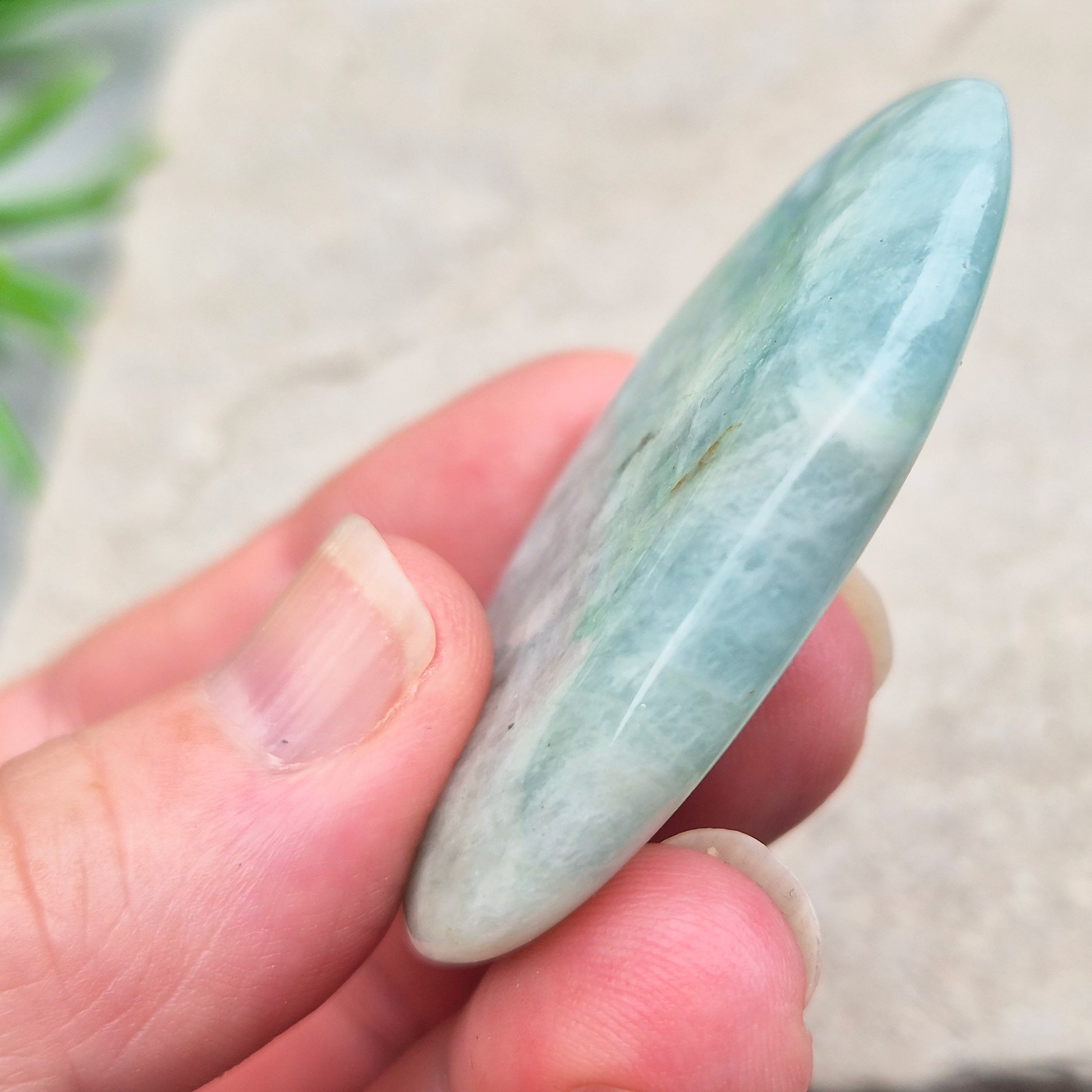 Aquamarine palm stone in pale aqua-blue, polished smooth. A calming crystal linked to the throat chakra, ideal for clearer thinking and honest conversations.