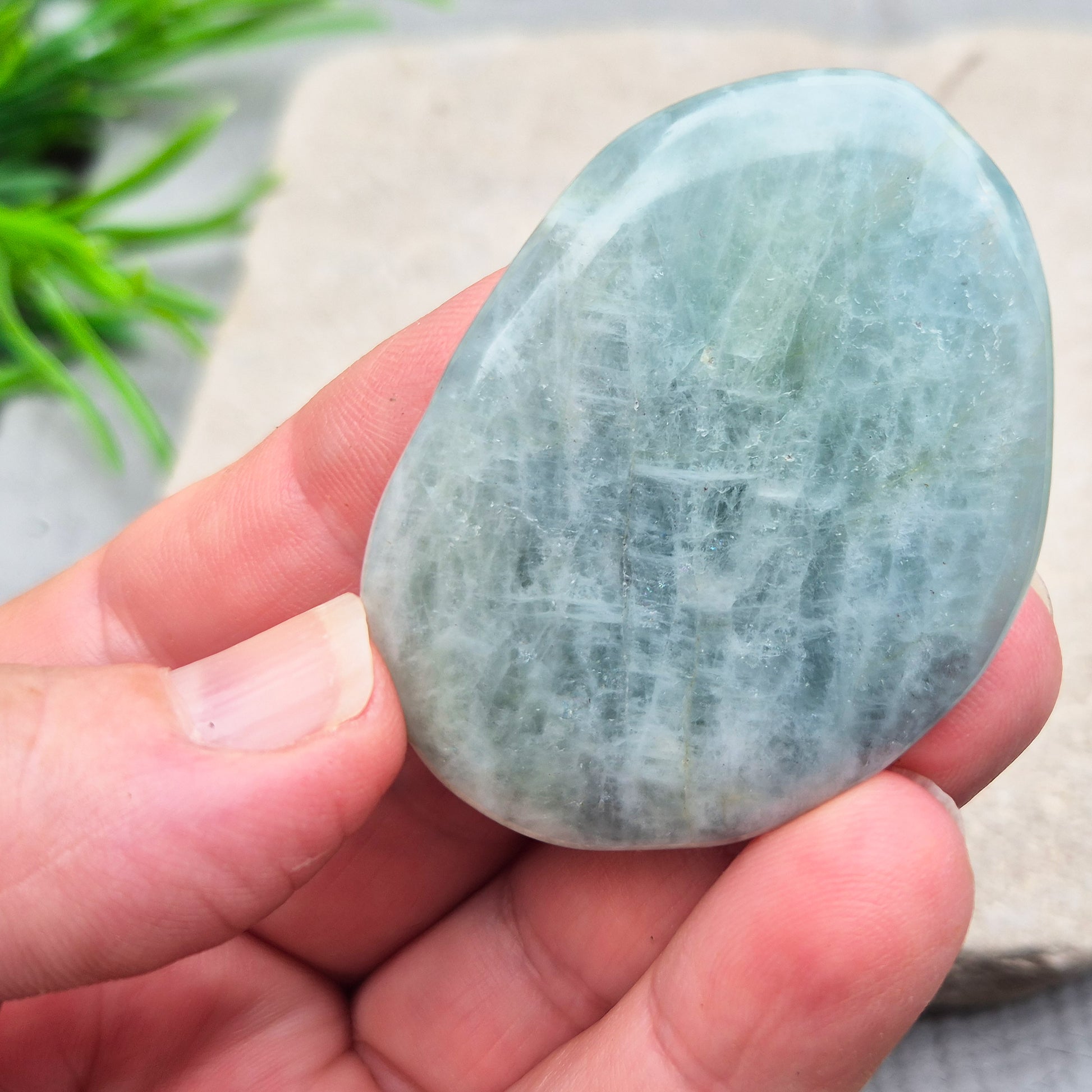Aquamarine palm stone in pale aqua-blue, polished smooth. A calming crystal linked to the throat chakra, ideal for clearer thinking and honest conversations.