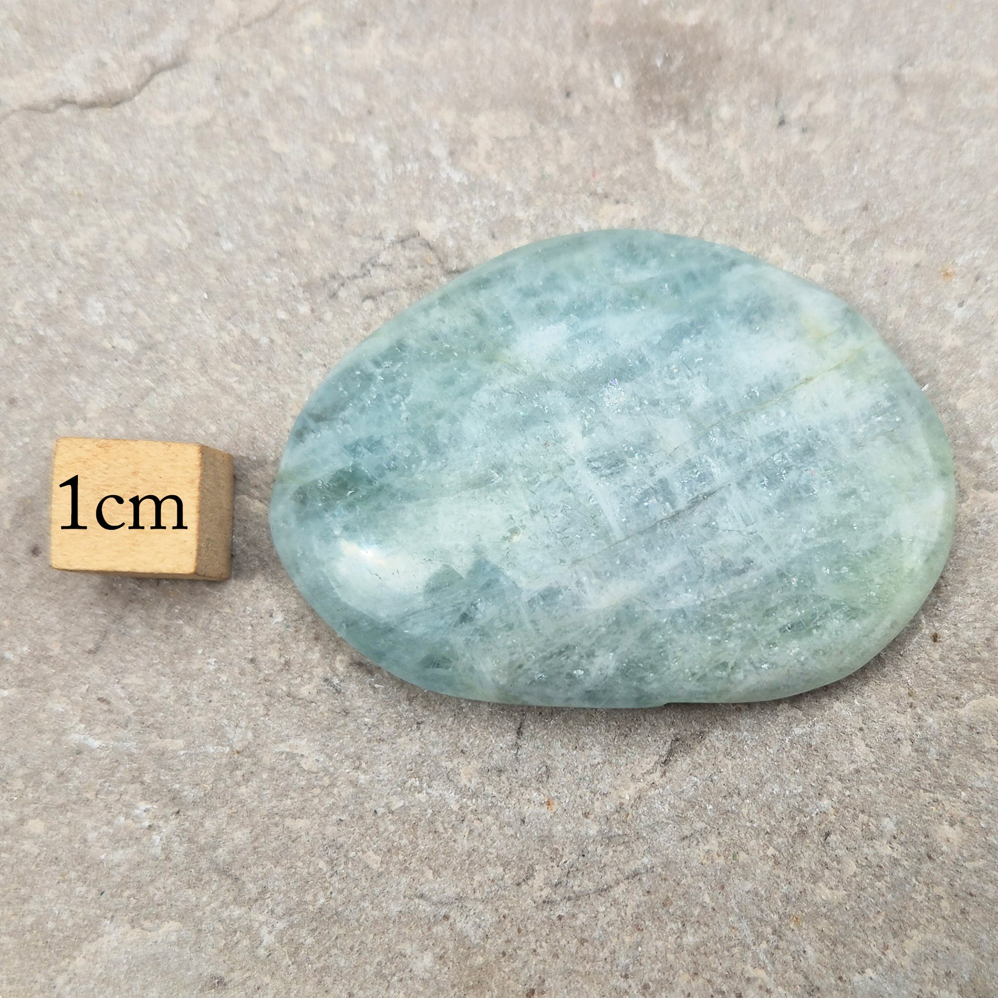 Aquamarine palm stone in pale aqua-blue, polished smooth. A calming crystal linked to the throat chakra, ideal for clearer thinking and honest conversations.