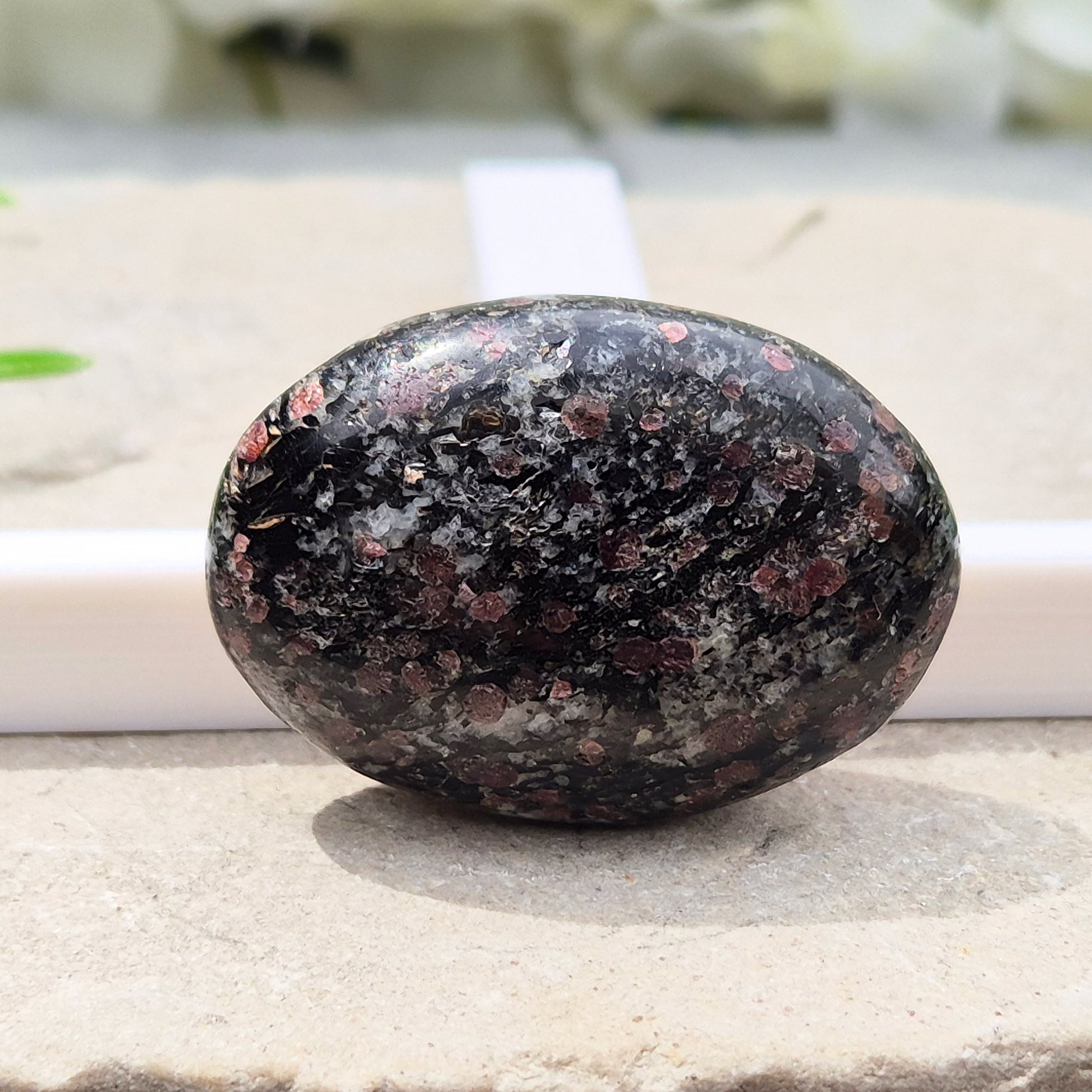 red Garnet in Black Tourmaline palm stone — naturally formed, said to bring grounding, courage and inner strength. Shop UK crystals at Elysian Crystals.