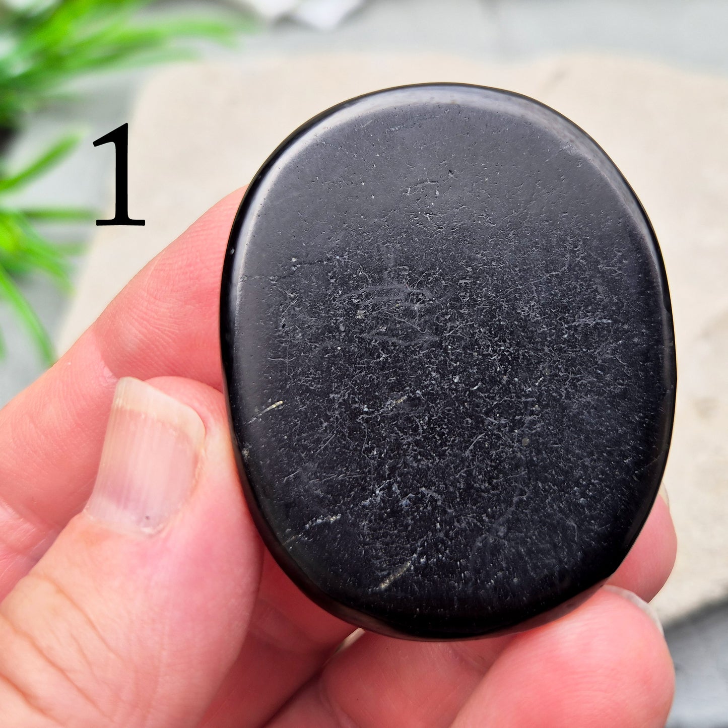 This polished Shungite Palm Stone has been shaped into a flat form that sits comfortably in the hand, with a solid, grounding feel to it. 