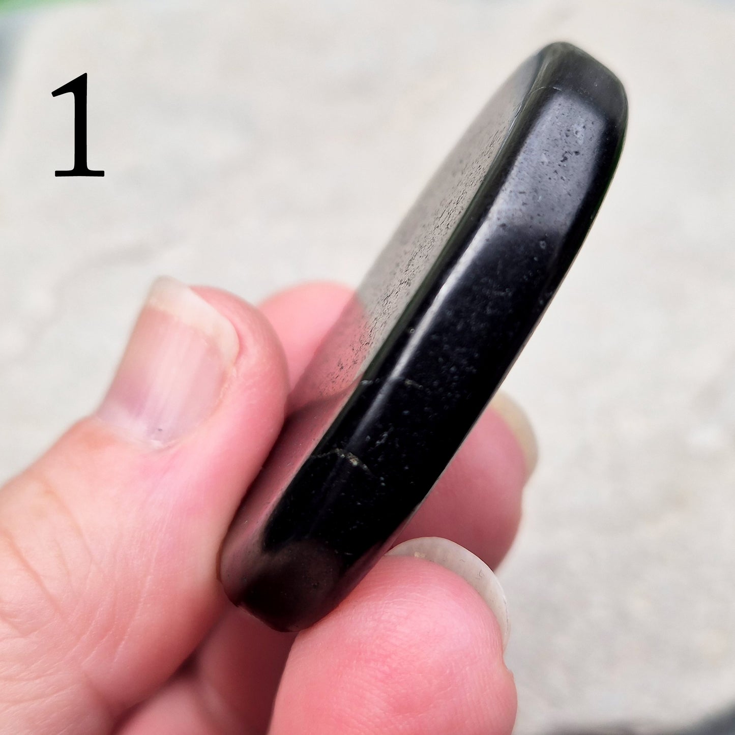 This polished Shungite Palm Stone has been shaped into a flat form that sits comfortably in the hand, with a solid, grounding feel to it. 