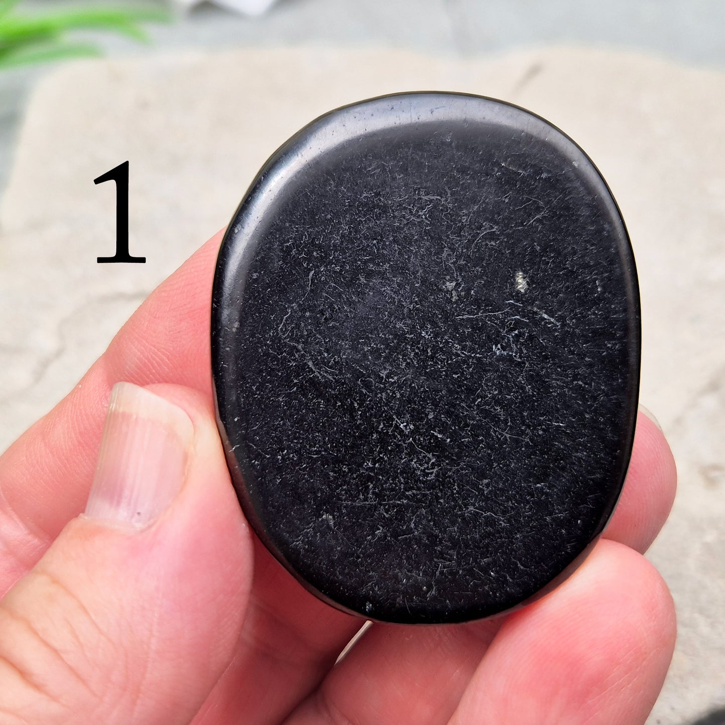This polished Shungite Palm Stone has been shaped into a flat form that sits comfortably in the hand, with a solid, grounding feel to it. 