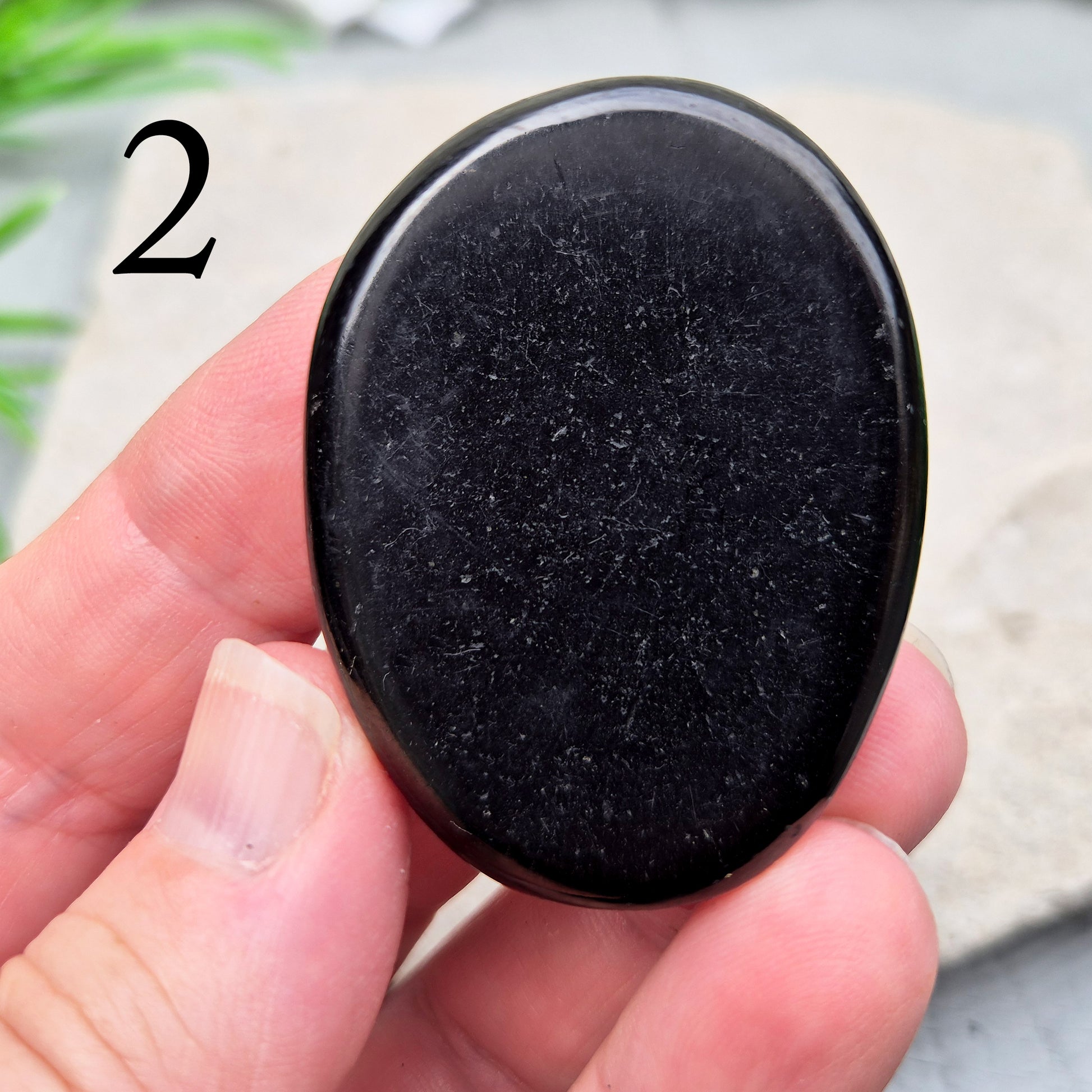 This polished Shungite Palm Stone has been shaped into a flat form that sits comfortably in the hand, with a solid, grounding feel to it. 