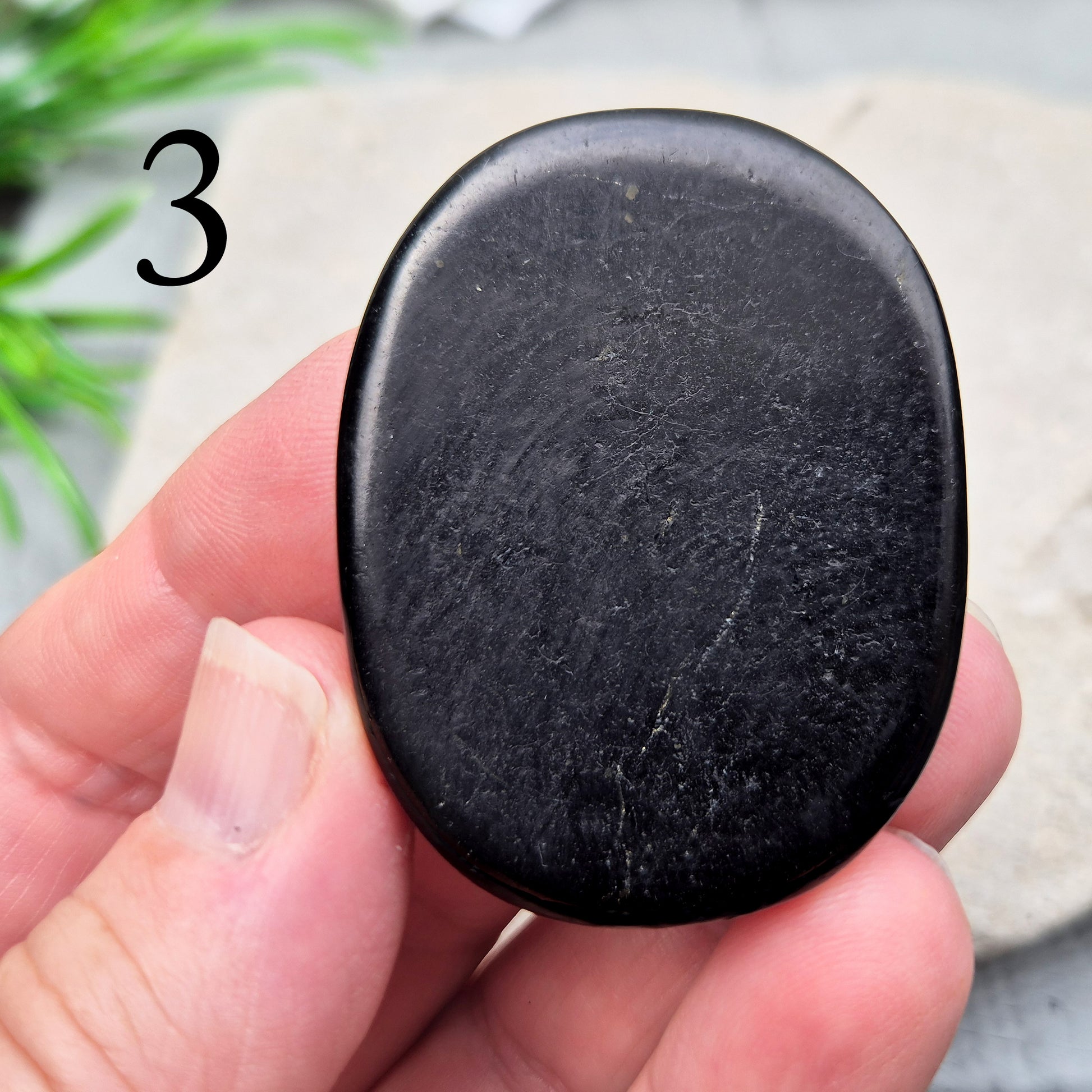 This polished Shungite Palm Stone has been shaped into a flat form that sits comfortably in the hand, with a solid, grounding feel to it. 