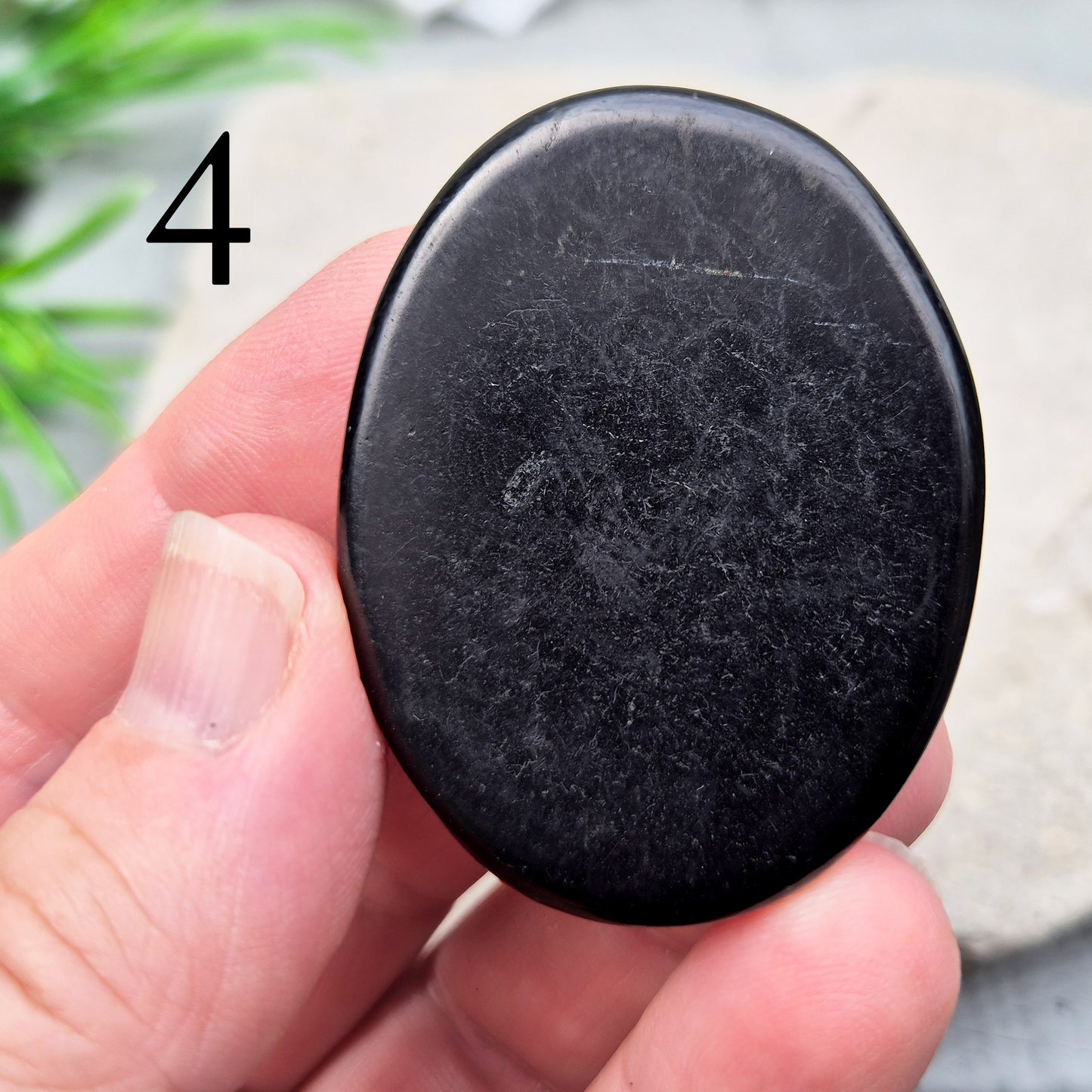This polished Shungite Palm Stone has been shaped into a flat form that sits comfortably in the hand, with a solid, grounding feel to it. 