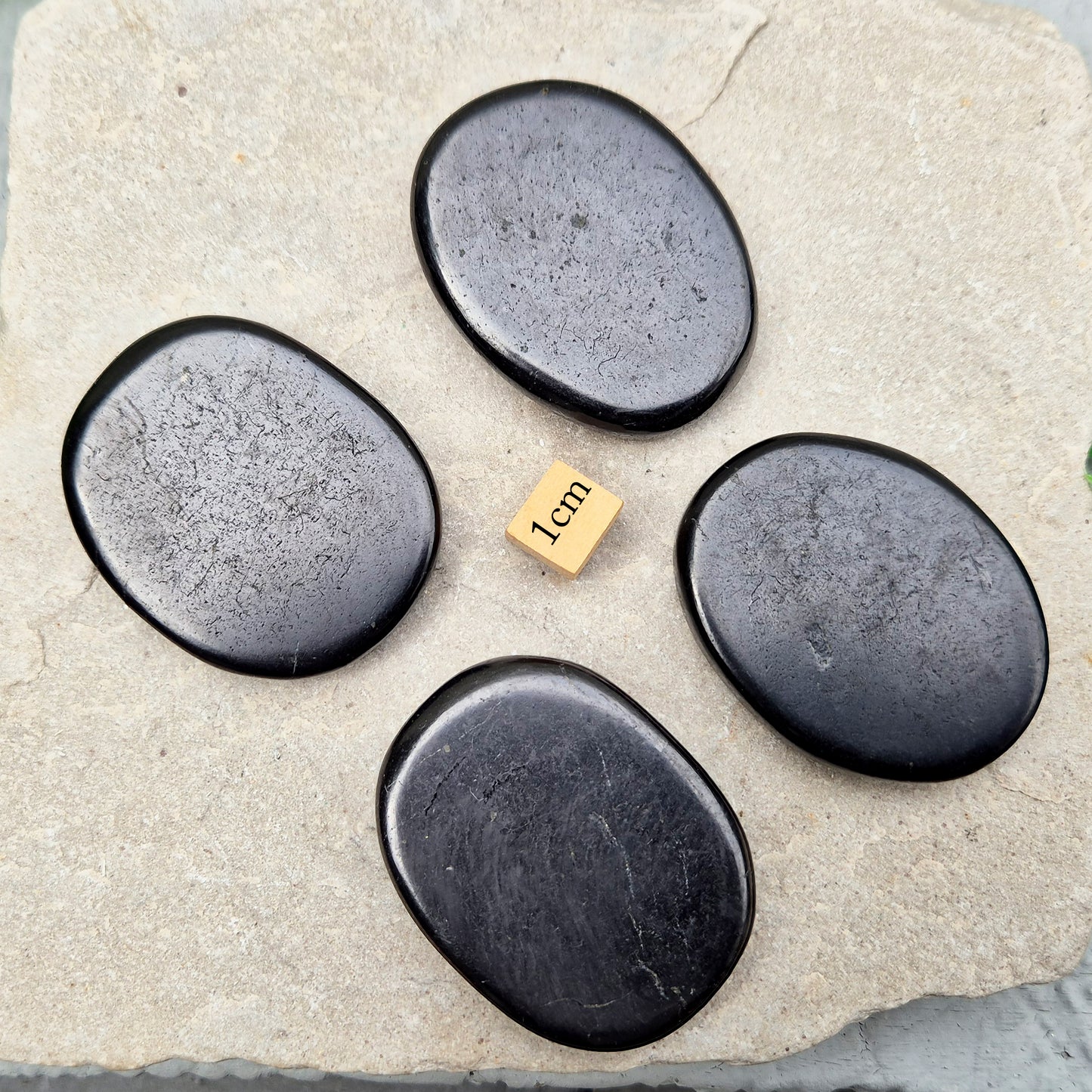 This polished Shungite Palm Stone has been shaped into a flat form that sits comfortably in the hand, with a solid, grounding feel to it. 