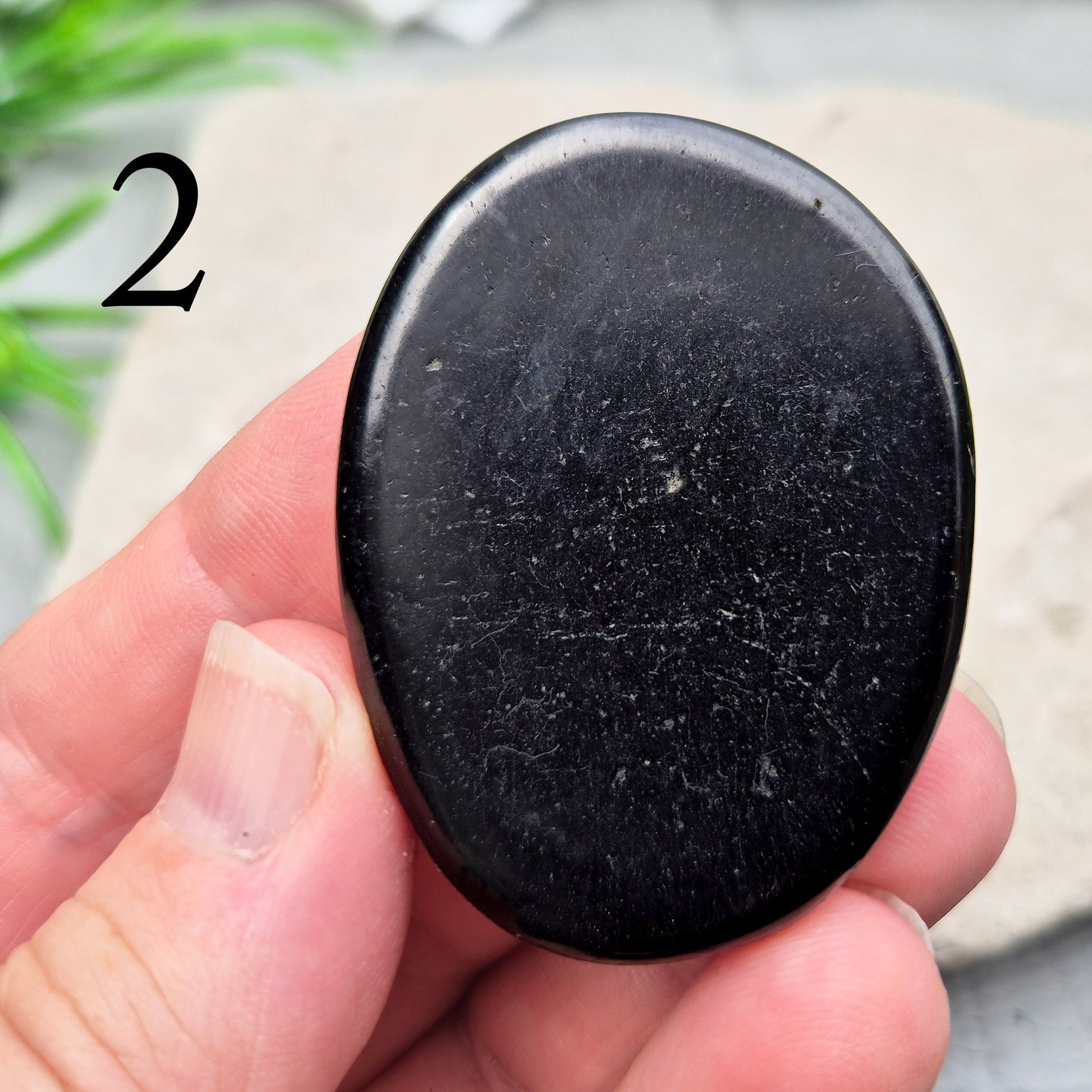 This polished Shungite Palm Stone has been shaped into a flat form that sits comfortably in the hand, with a solid, grounding feel to it. 