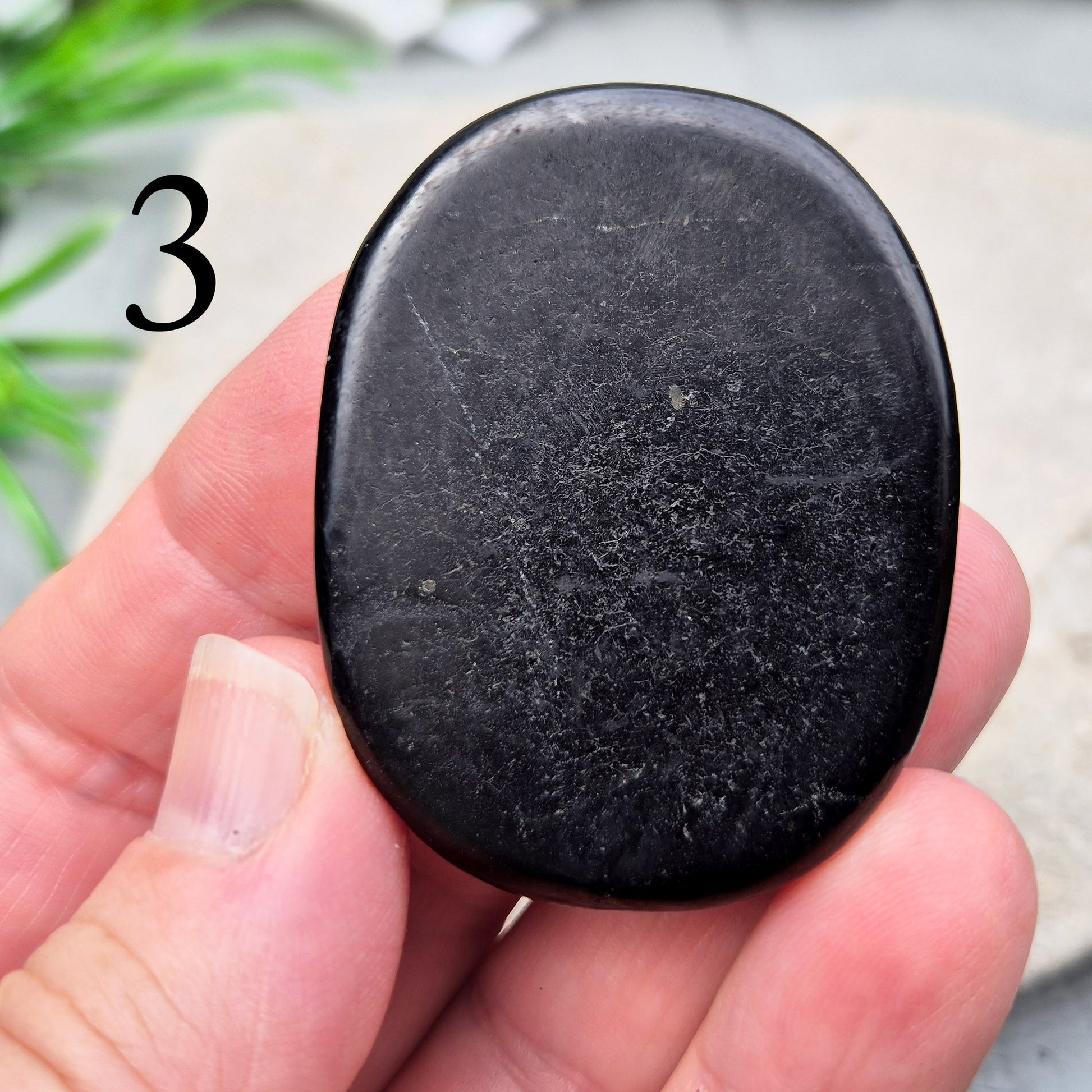 This polished Shungite Palm Stone has been shaped into a flat form that sits comfortably in the hand, with a solid, grounding feel to it. 