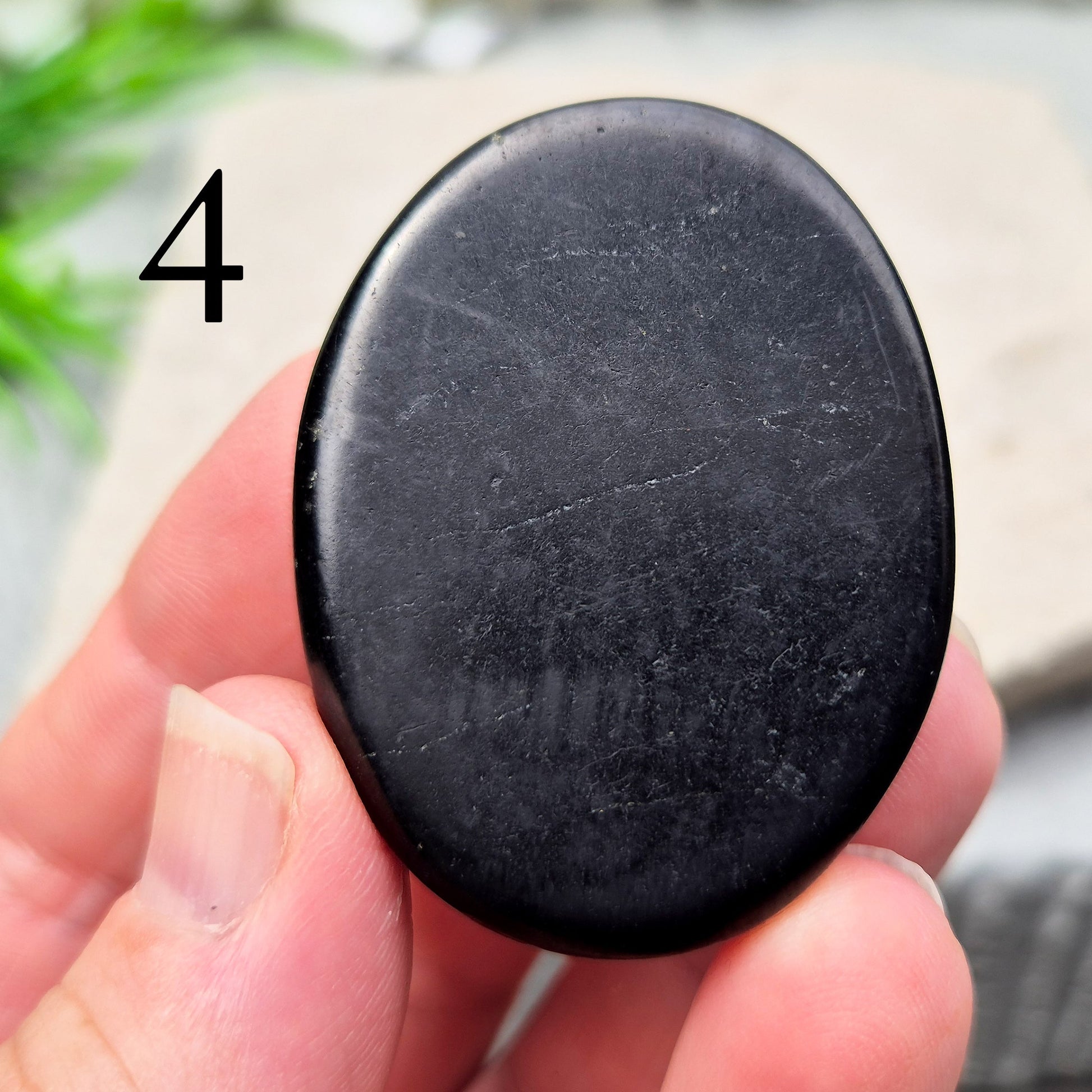 This polished Shungite Palm Stone has been shaped into a flat form that sits comfortably in the hand, with a solid, grounding feel to it. 
