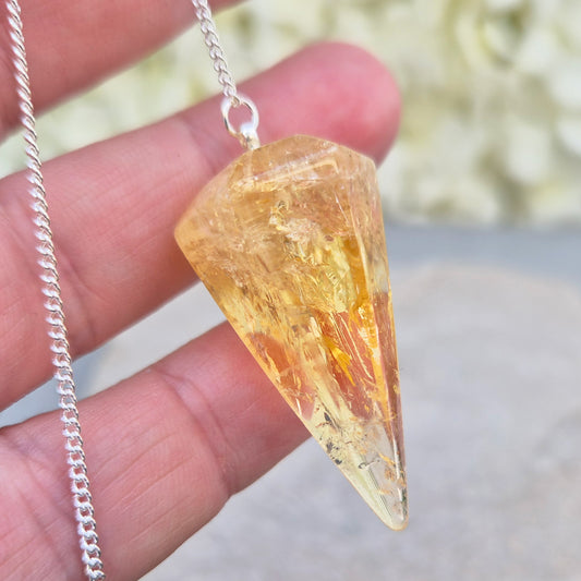 Citrine Crystal Pendulum from Brazil. This stunning sunny pendulum carrys the warm, golden glow Citrine is loved for. It has a yellow bead at the end of the chain making it comfortable to hold and easy to use.