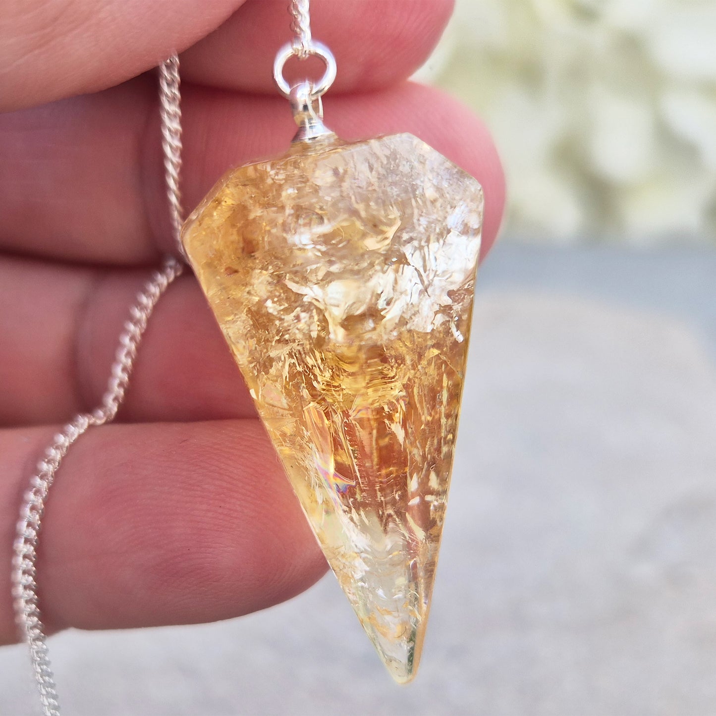 Citrine Crystal Pendulum from Brazil. This stunning sunny pendulum carrys the warm, golden glow Citrine is loved for. It has a yellow bead at the end of the chain making it comfortable to hold and easy to use.