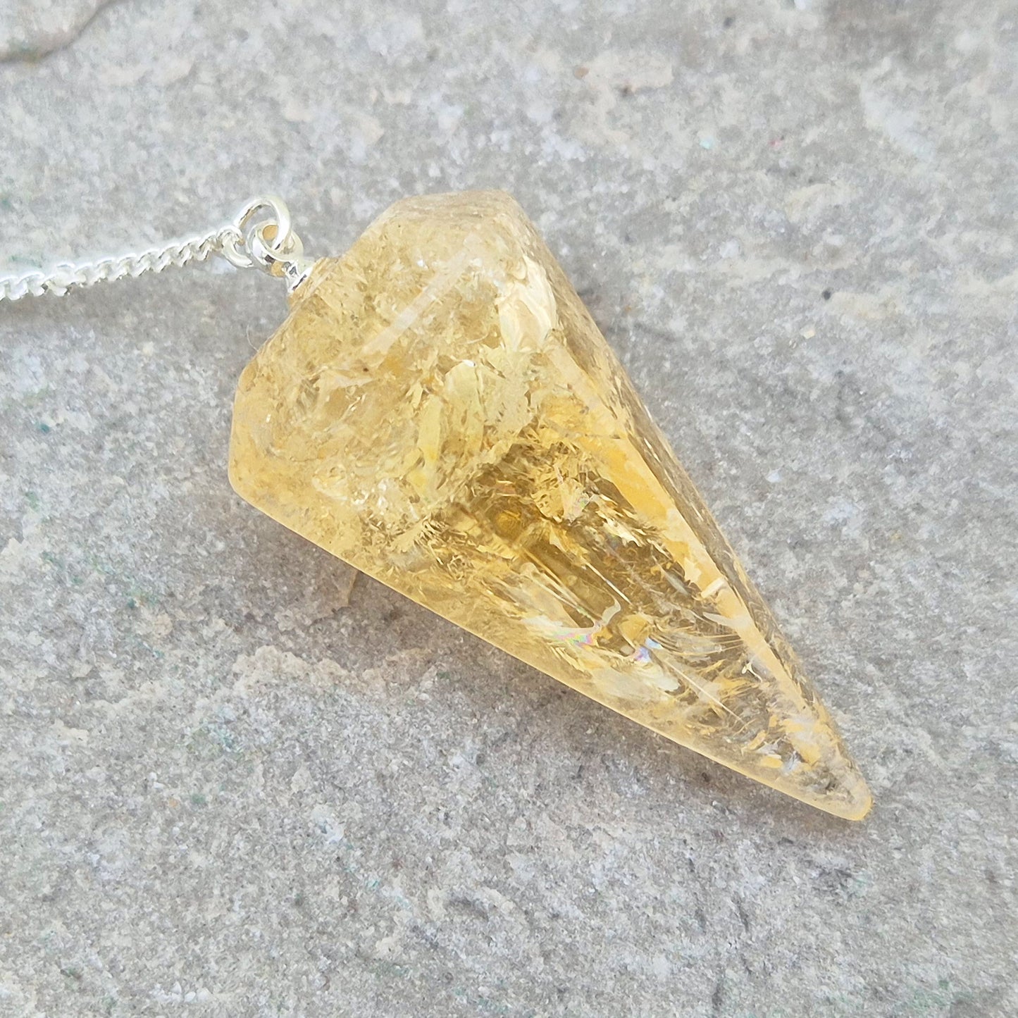 Citrine Crystal Pendulum from Brazil. This stunning sunny pendulum carrys the warm, golden glow Citrine is loved for. It has a yellow bead at the end of the chain making it comfortable to hold and easy to use.
