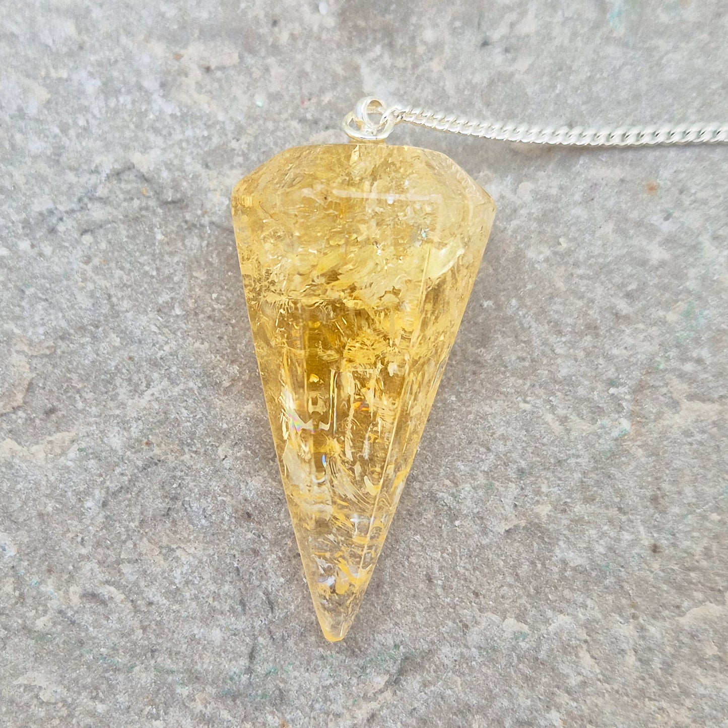 Citrine Crystal Pendulum from Brazil. This stunning sunny pendulum carrys the warm, golden glow Citrine is loved for. It has a yellow bead at the end of the chain making it comfortable to hold and easy to use.