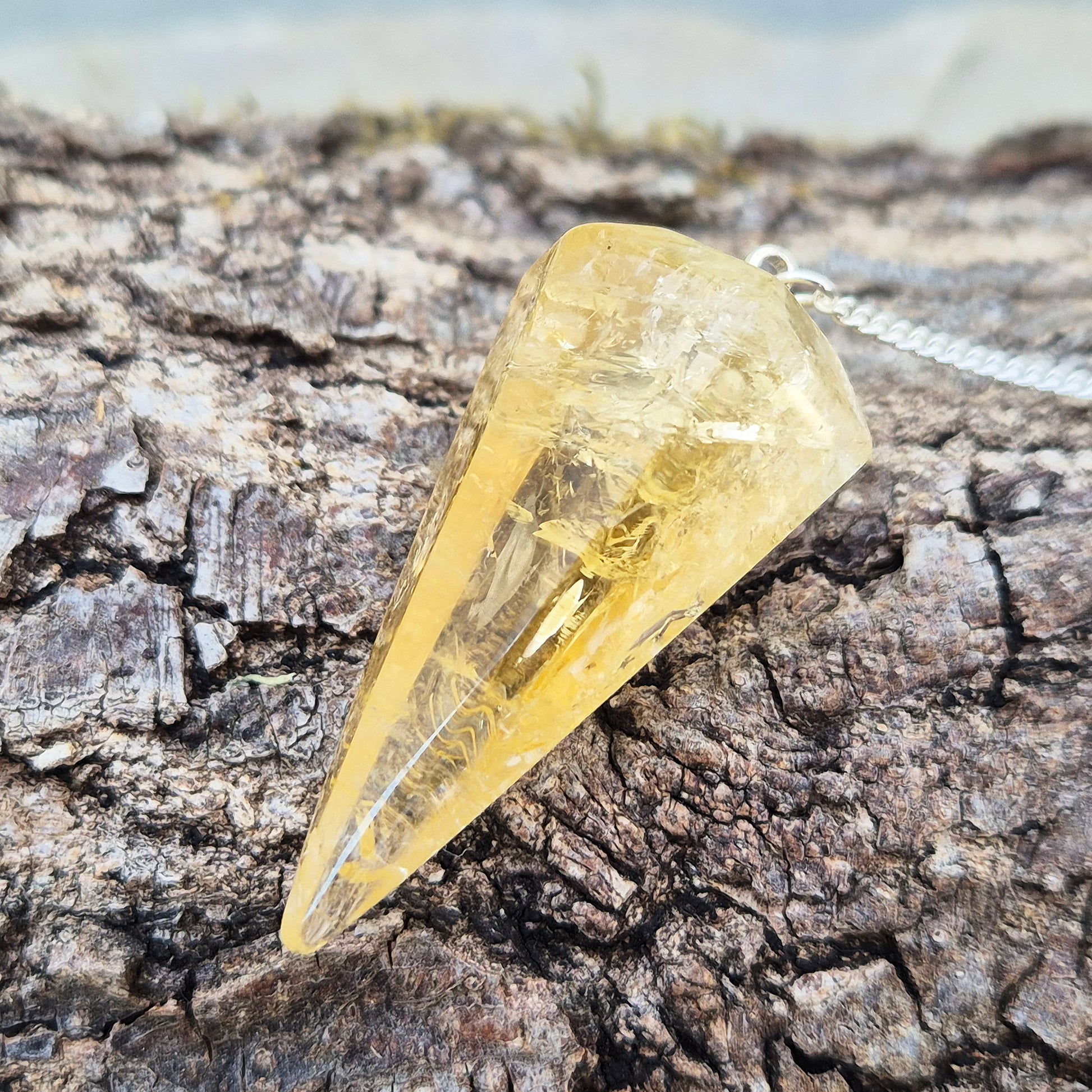 Citrine Crystal Pendulum from Brazil. This stunning sunny pendulum carrys the warm, golden glow Citrine is loved for. It has a yellow bead at the end of the chain making it comfortable to hold and easy to use.