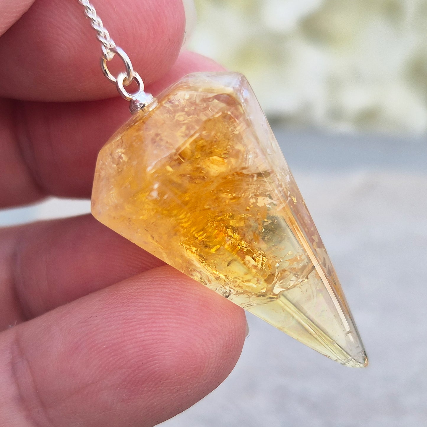 Citrine Crystal Pendulum from Brazil. This stunning sunny pendulum carrys the warm, golden glow Citrine is loved for. It has a yellow bead at the end of the chain making it comfortable to hold and easy to use.