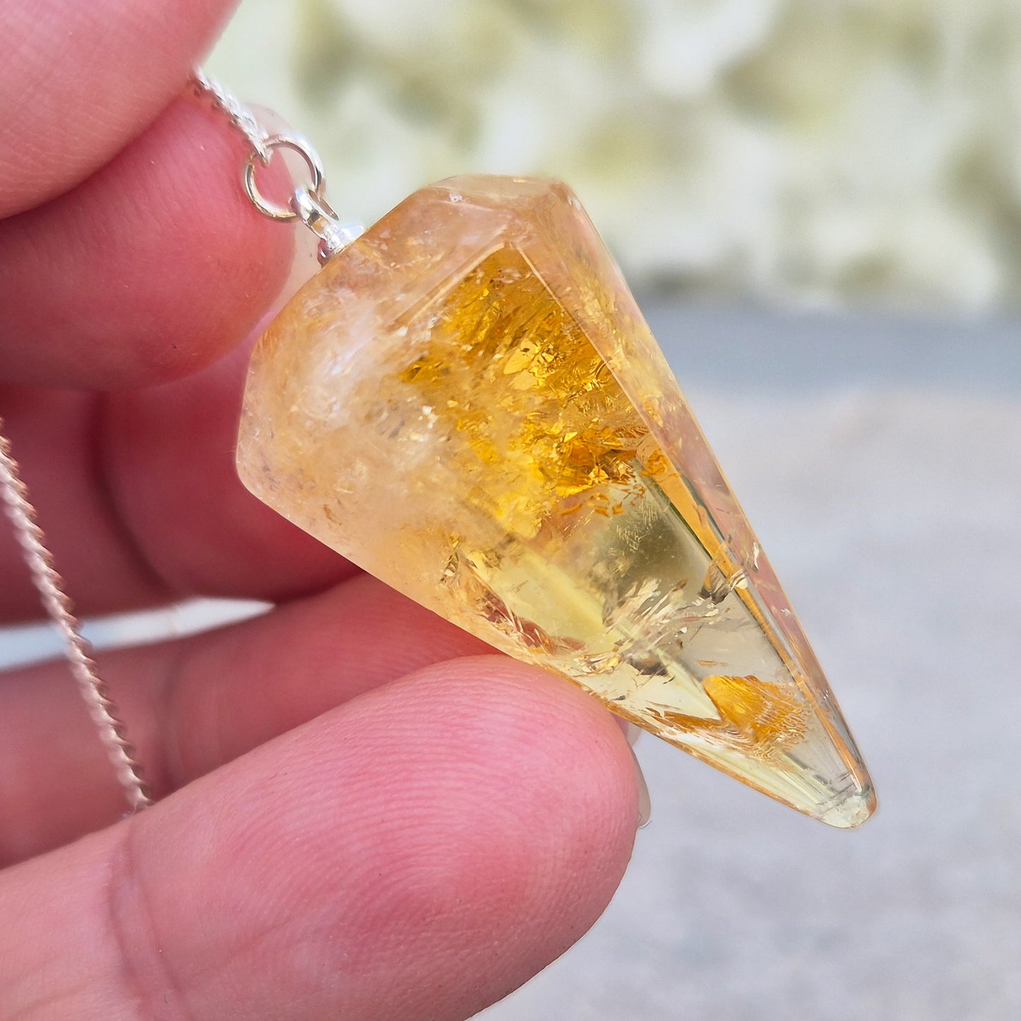 Citrine Crystal Pendulum from Brazil. This stunning sunny pendulum carrys the warm, golden glow Citrine is loved for. It has a yellow bead at the end of the chain making it comfortable to hold and easy to use.