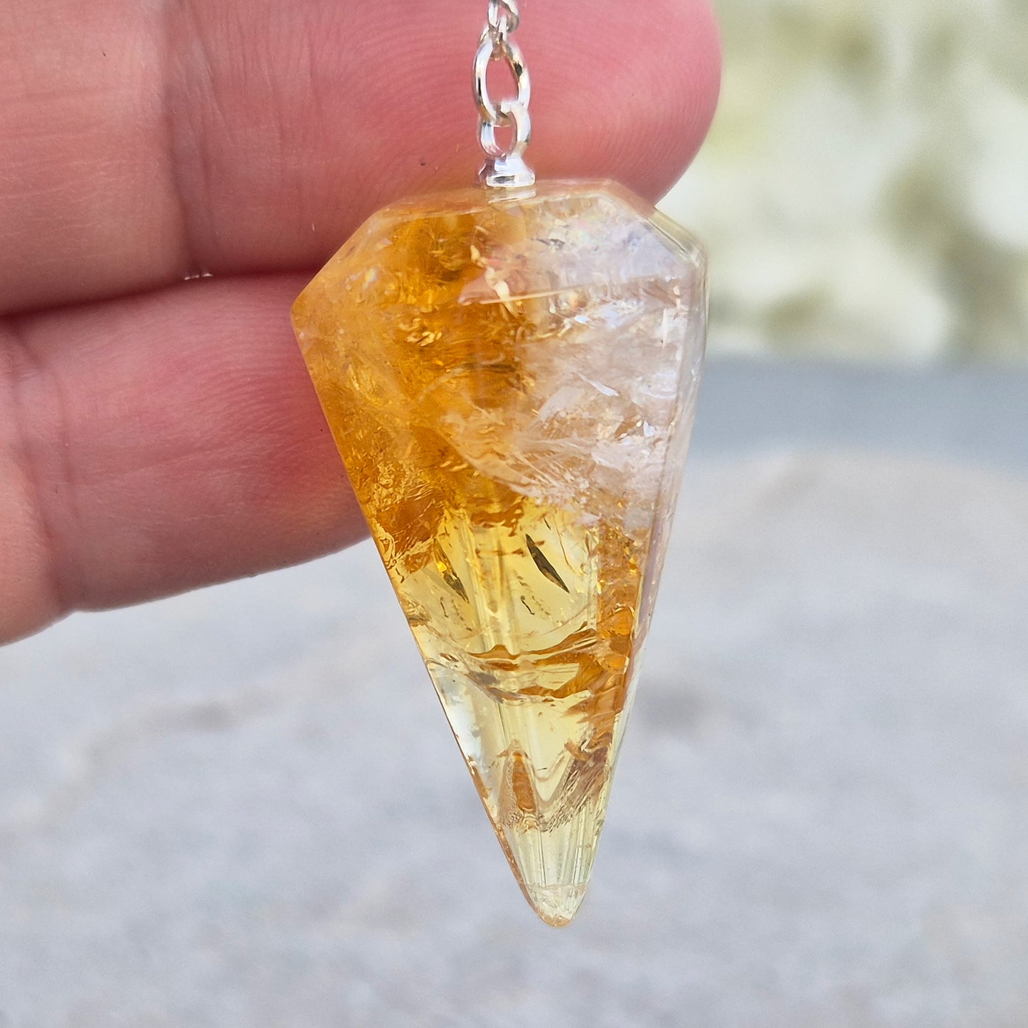 Citrine Crystal Pendulum from Brazil. This stunning sunny pendulum carrys the warm, golden glow Citrine is loved for. It has a yellow bead at the end of the chain making it comfortable to hold and easy to use.
