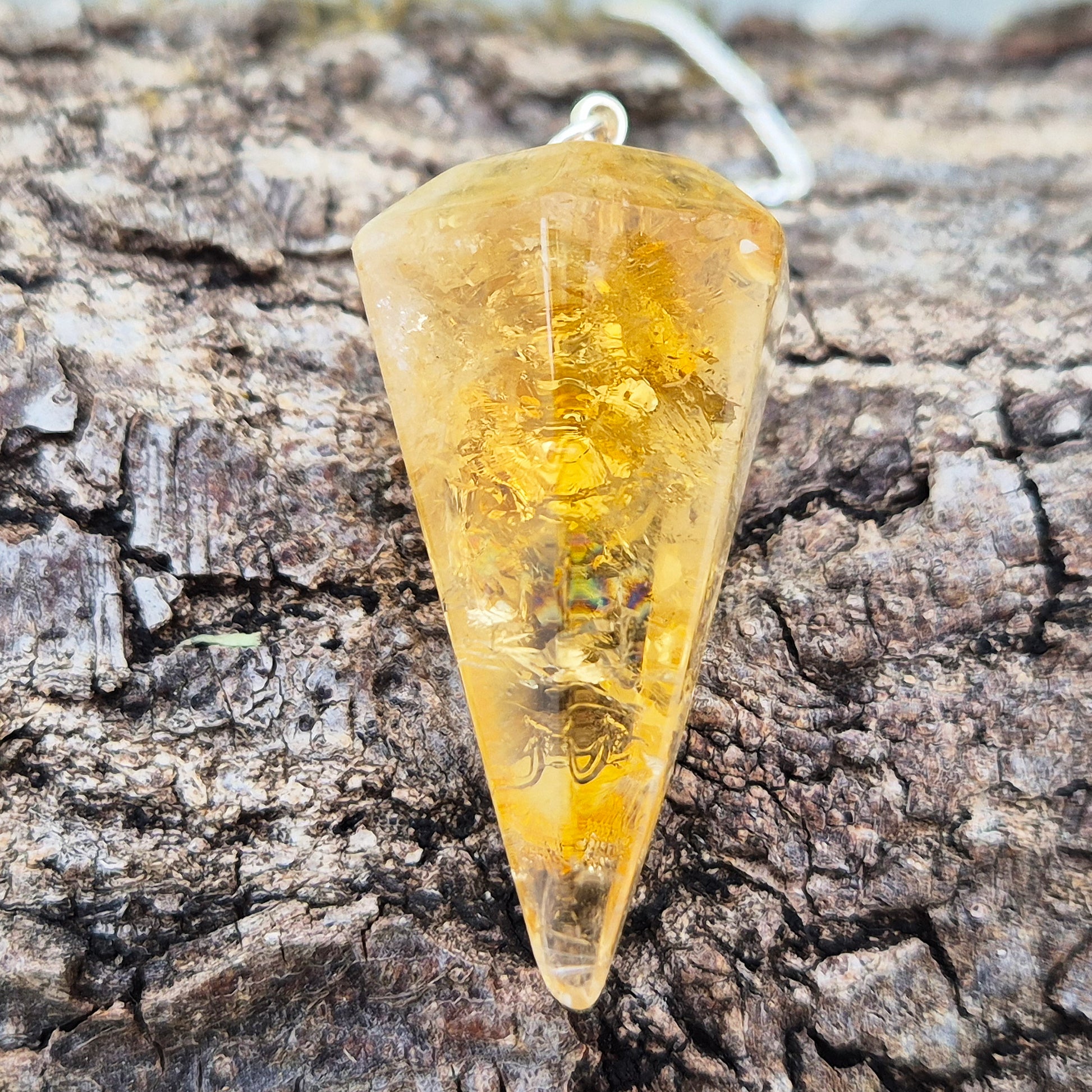 Citrine Crystal Pendulum from Brazil. This stunning sunny pendulum carrys the warm, golden glow Citrine is loved for. It has a yellow bead at the end of the chain making it comfortable to hold and easy to use.